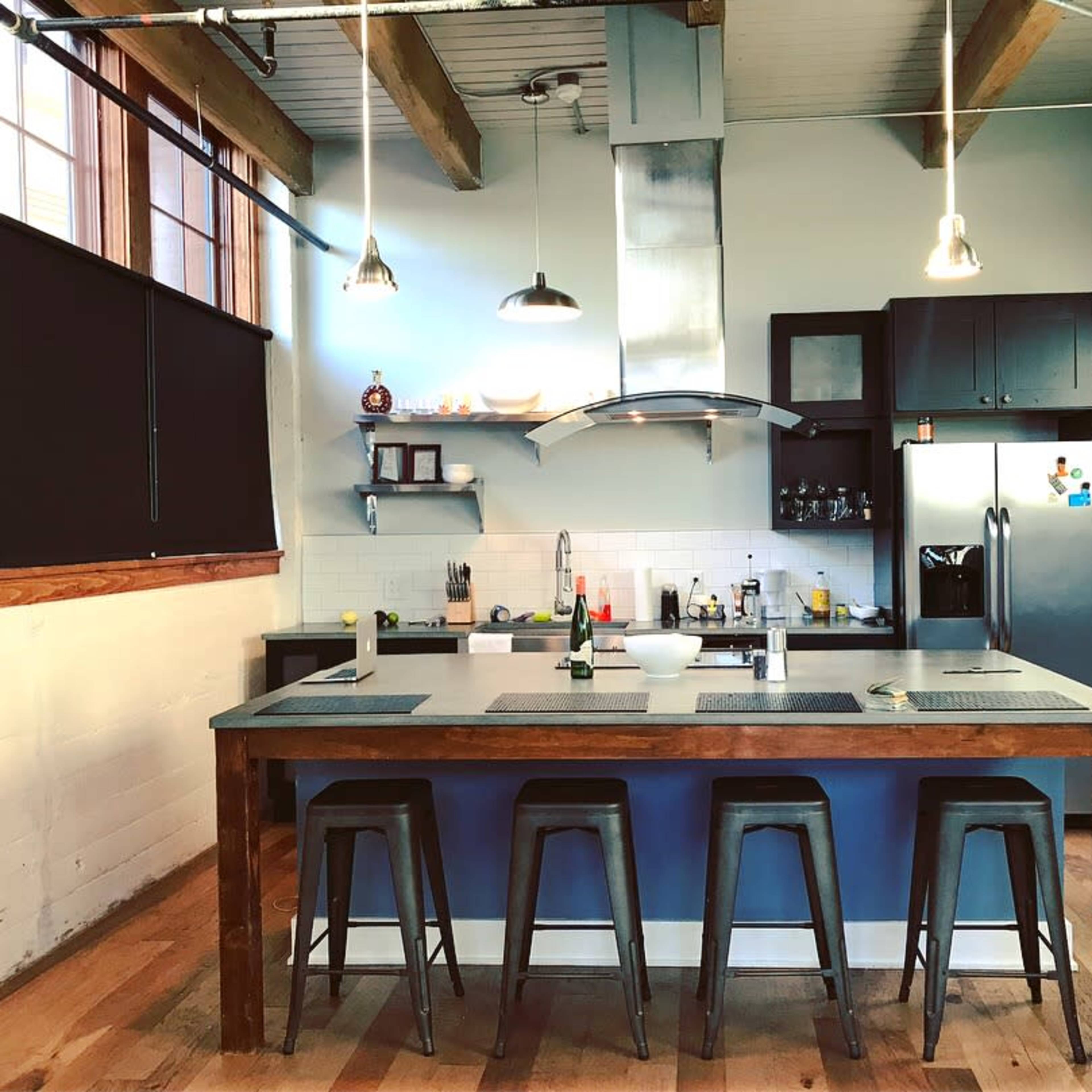 A modern kitchen with a large central island, bar stools, and stainless steel appliances.