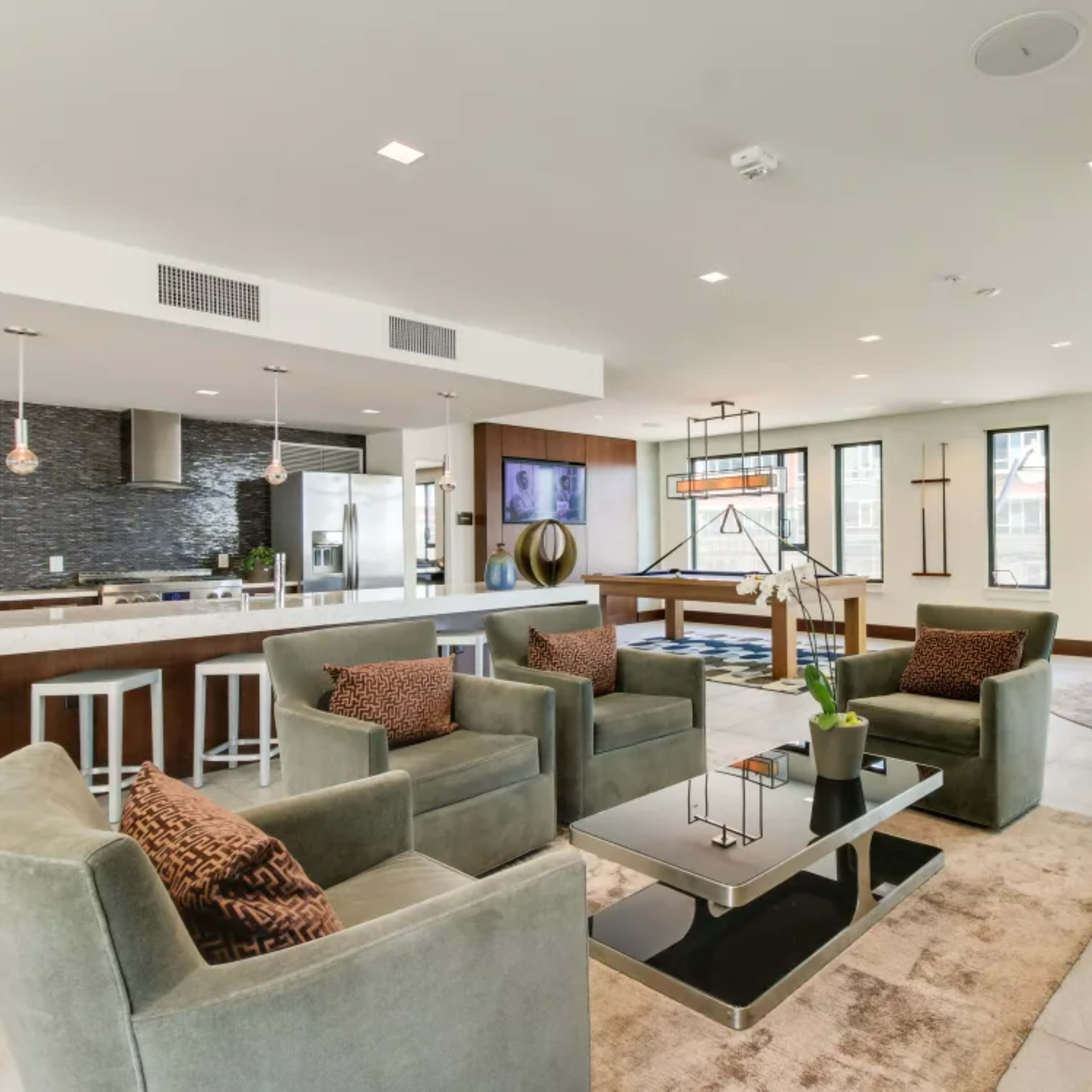 A modern communal lounge area featuring seating, a coffee table, and large windows.
