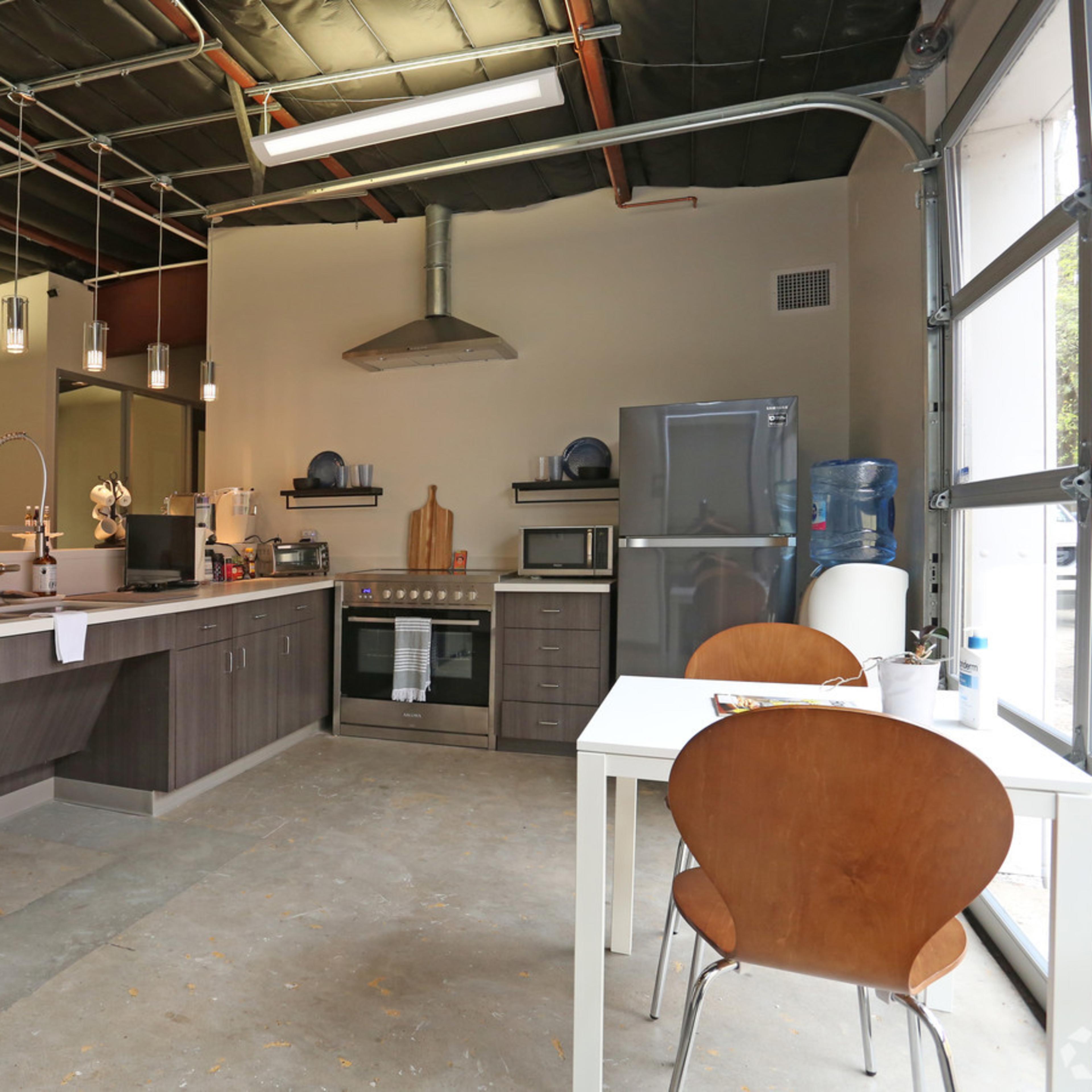 A modern kitchen with stainless steel appliances, a central island, and a dining table set for two.