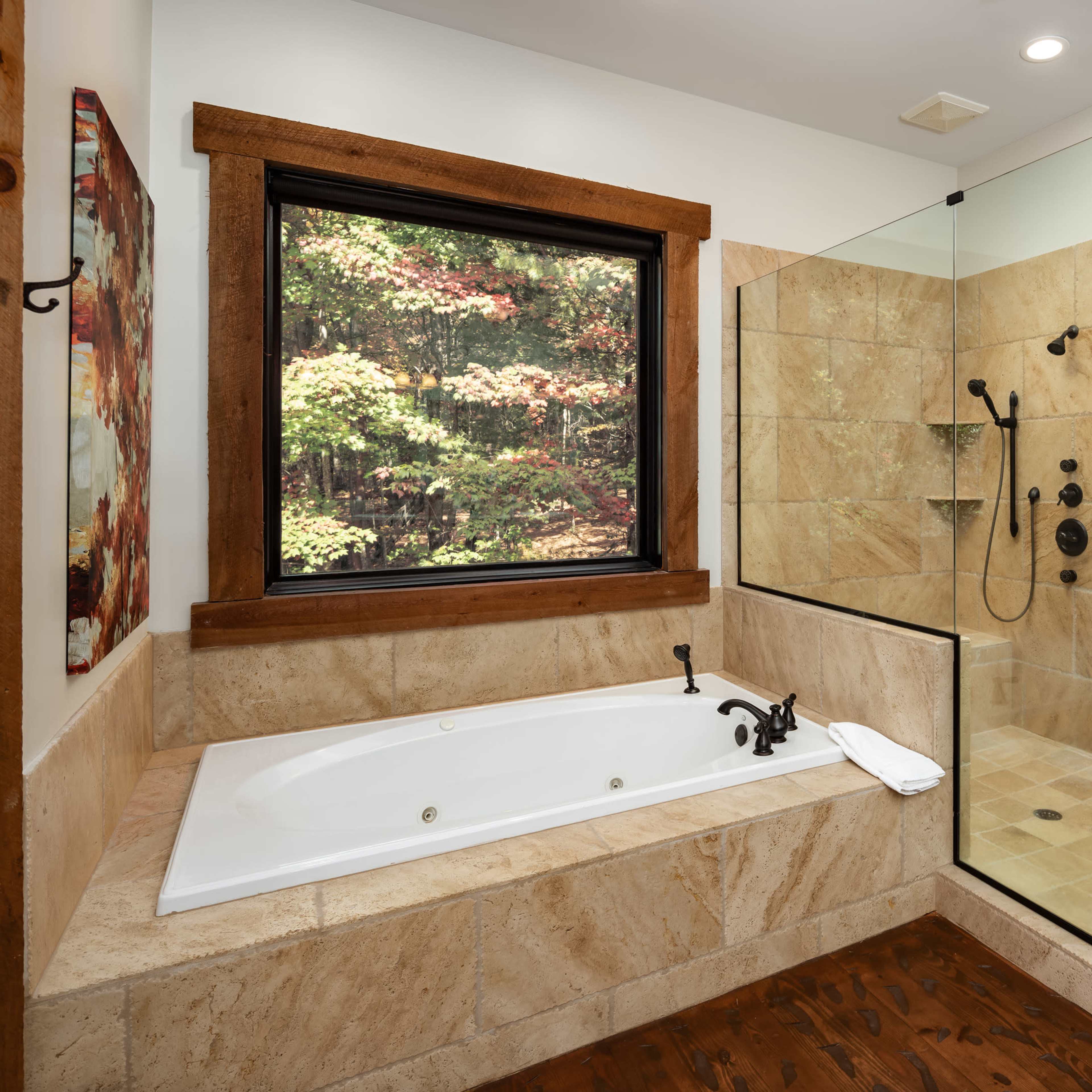 A modern bathroom featuring a freestanding bathtub beside a glass-enclosed shower with natural stone walls and wooden accents.