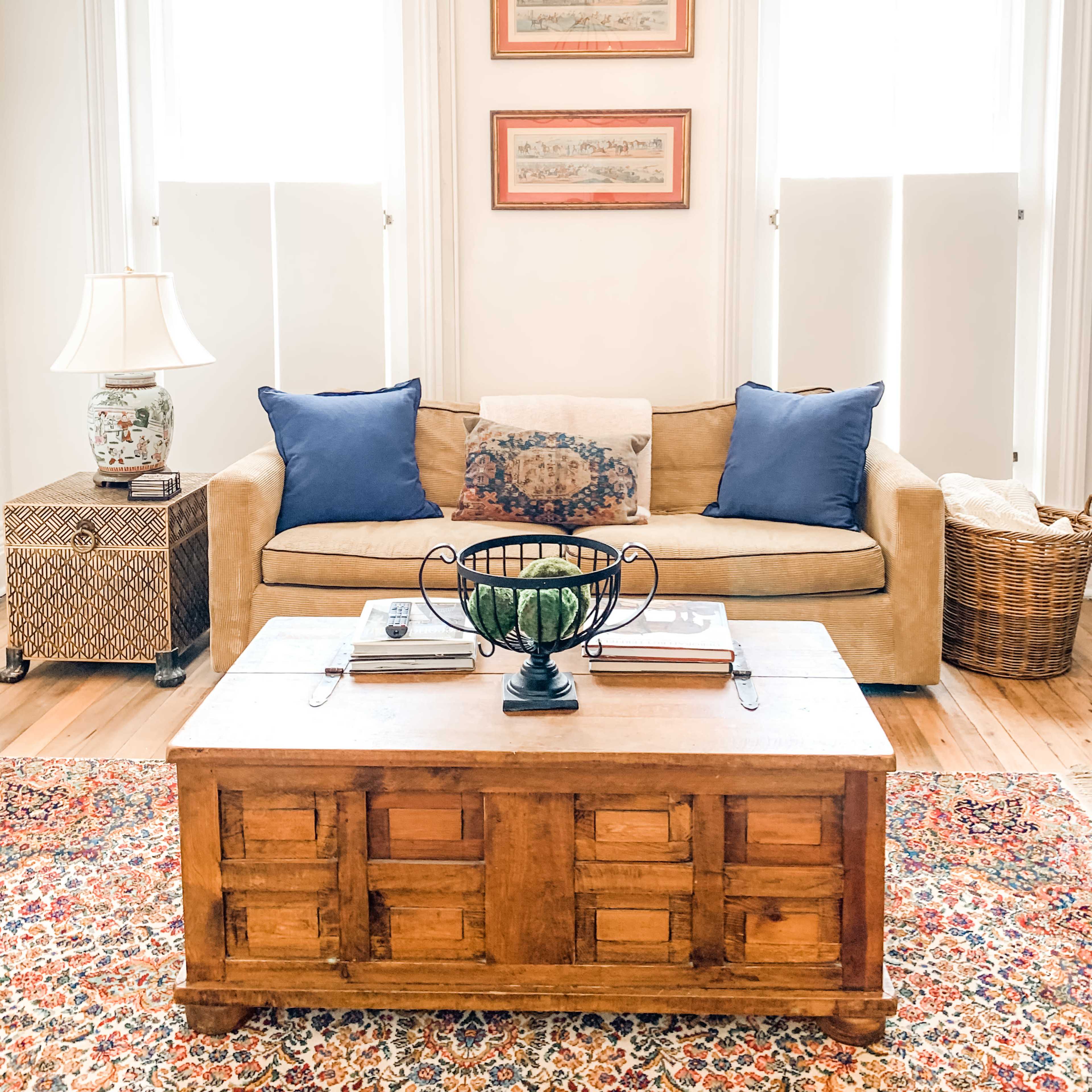 A cozy living room featuring a beige sofa with blue pillows, a wooden coffee table, and a decorative rug under a chandelier.
