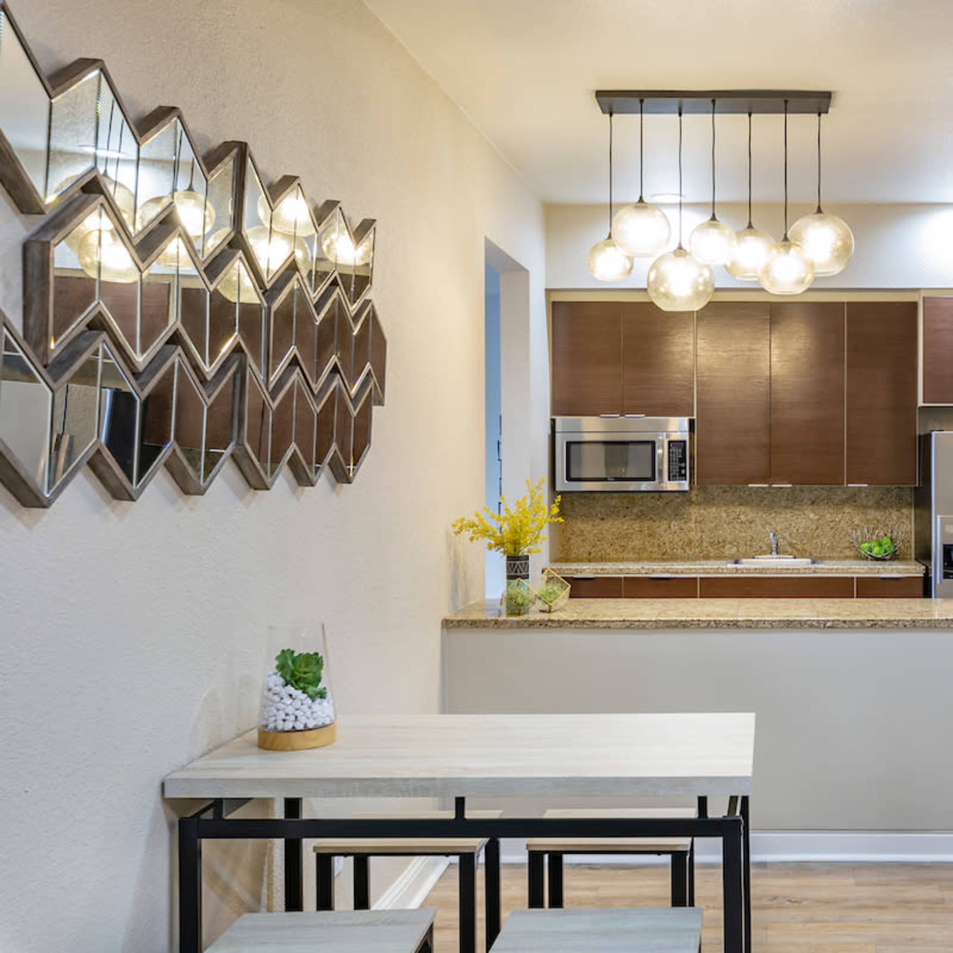 A modern kitchen with wooden cabinetry, stainless steel appliances, and a dining area featuring a small table and benches.