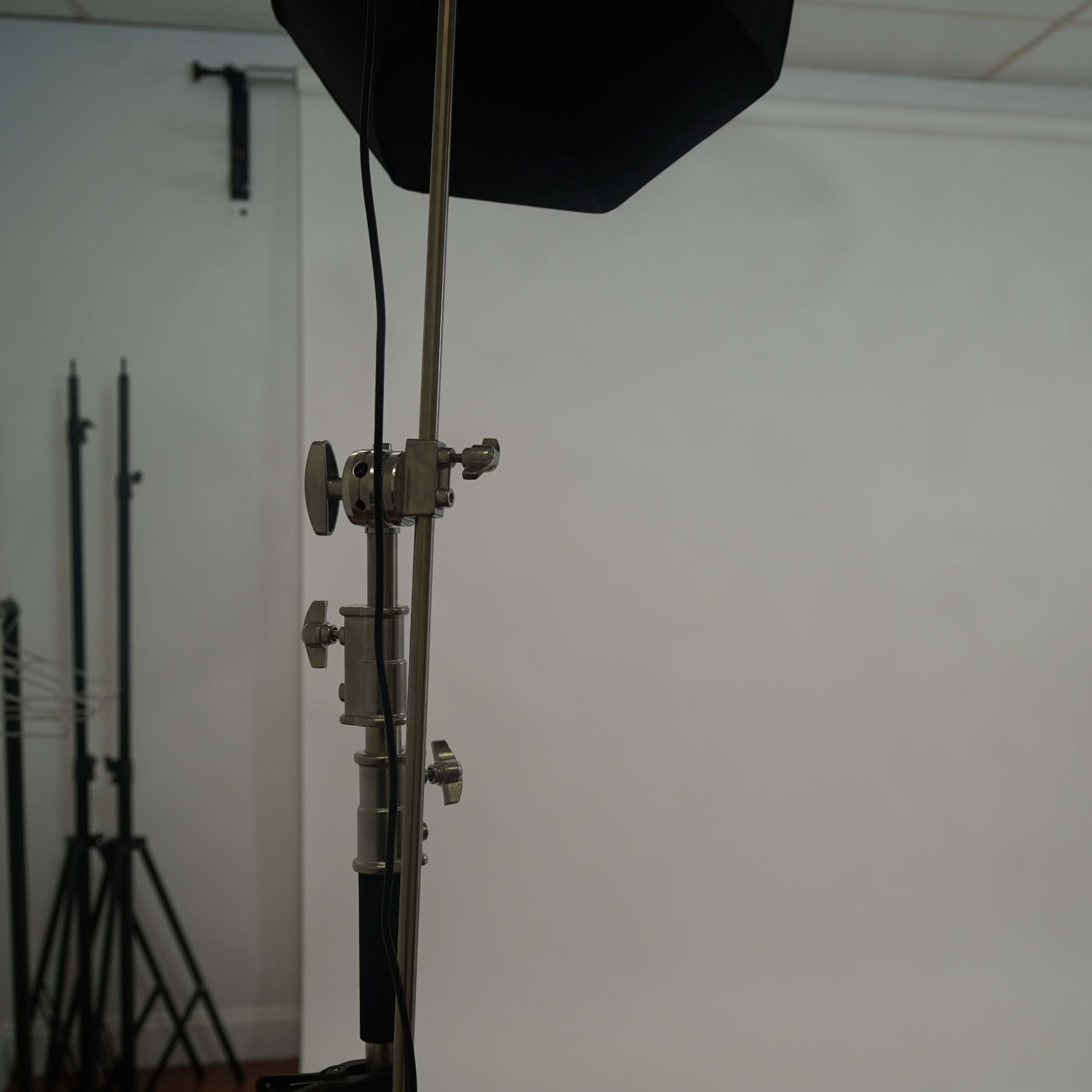 A photography studio setup featuring a backdrop, lighting equipment, and a folding chair.