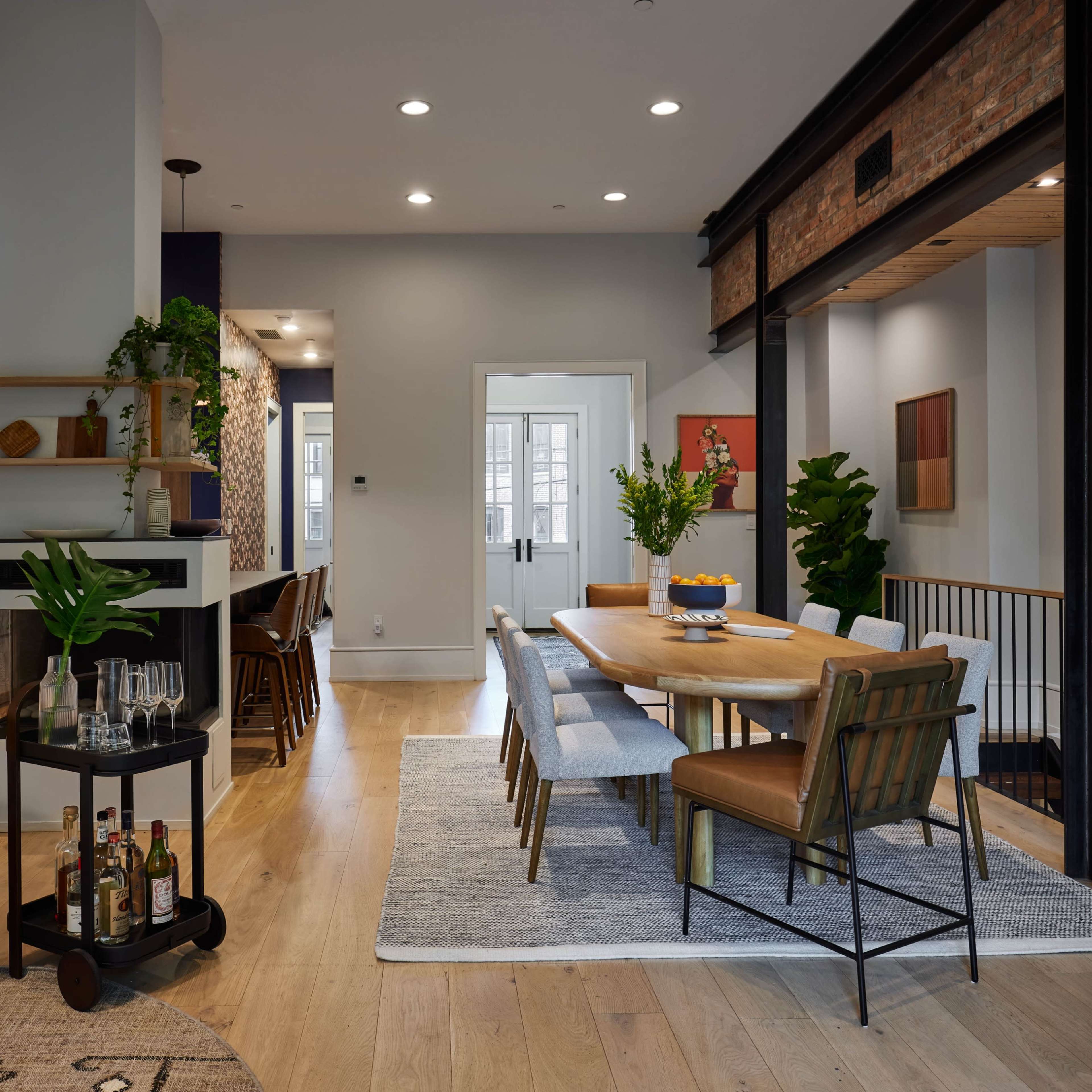 A modern open-concept living and dining area featuring a wooden dining table, stylish seating, and decorative plants.