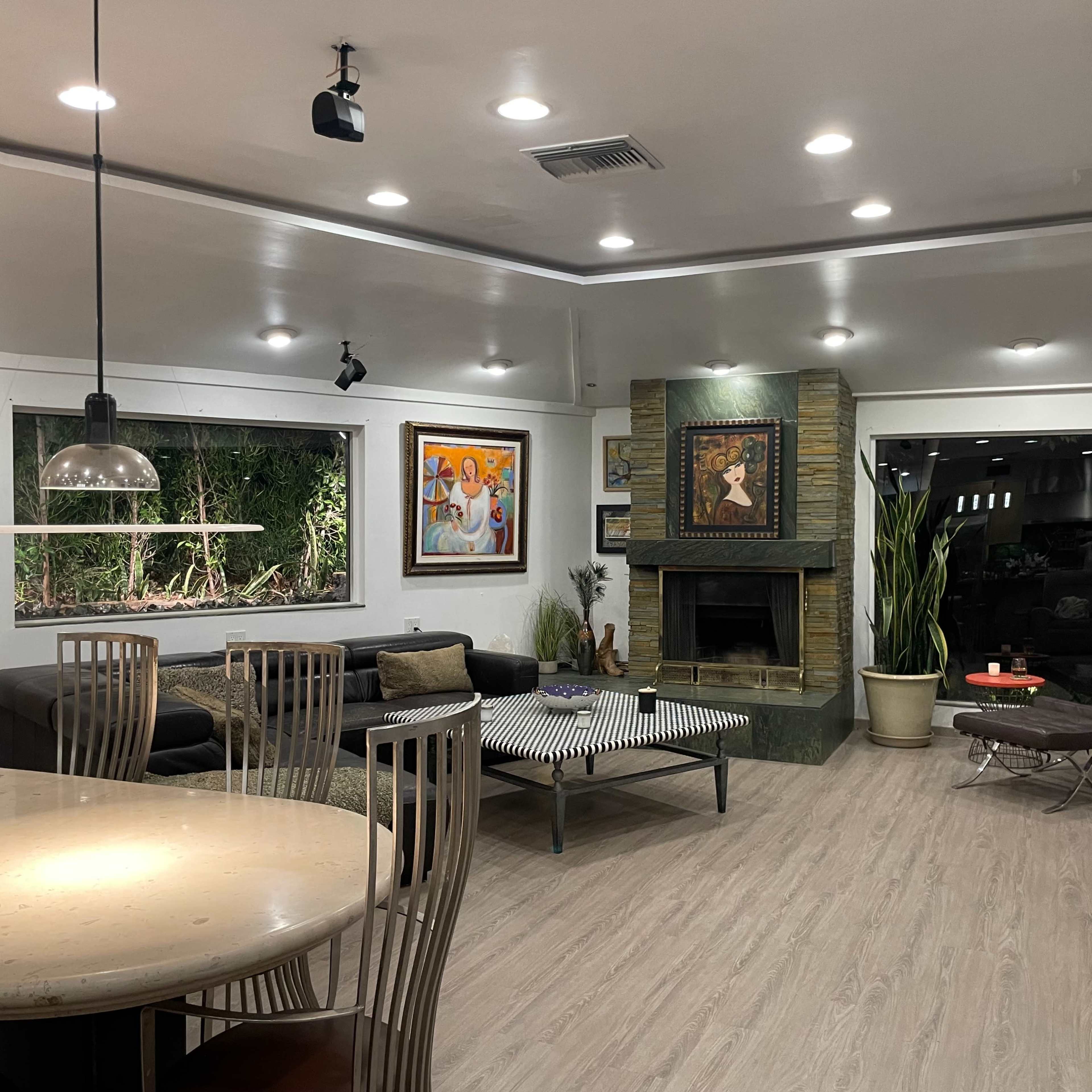 A modern living room with artwork on the walls, a dark sofa, a coffee table, and a stone fireplace.