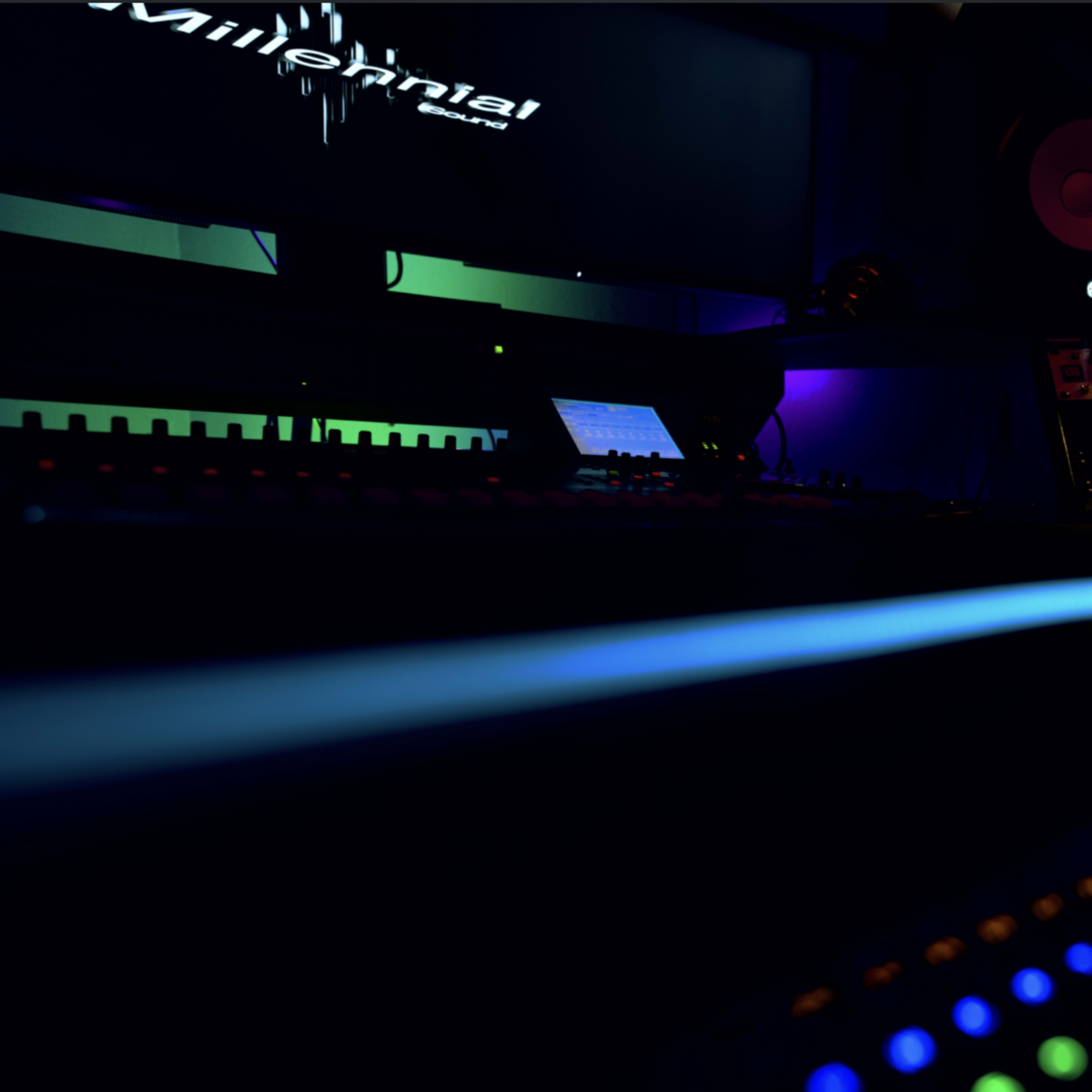 A dimly lit music studio with colorful LED lights illuminating the control panel and audio mixing equipment.