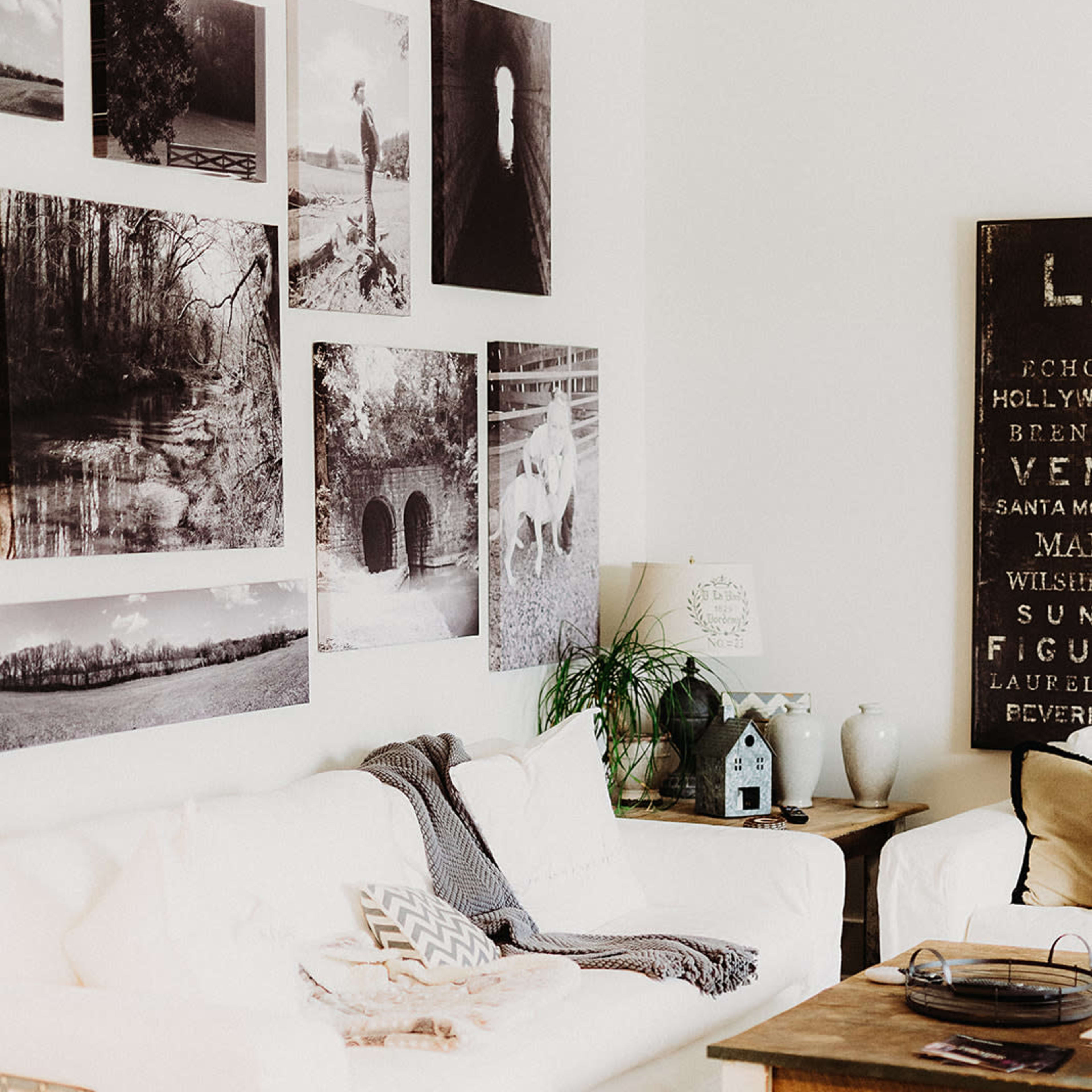 A cozy living room with a white couch, a wooden coffee table, and a wall adorned with black and white photographs.