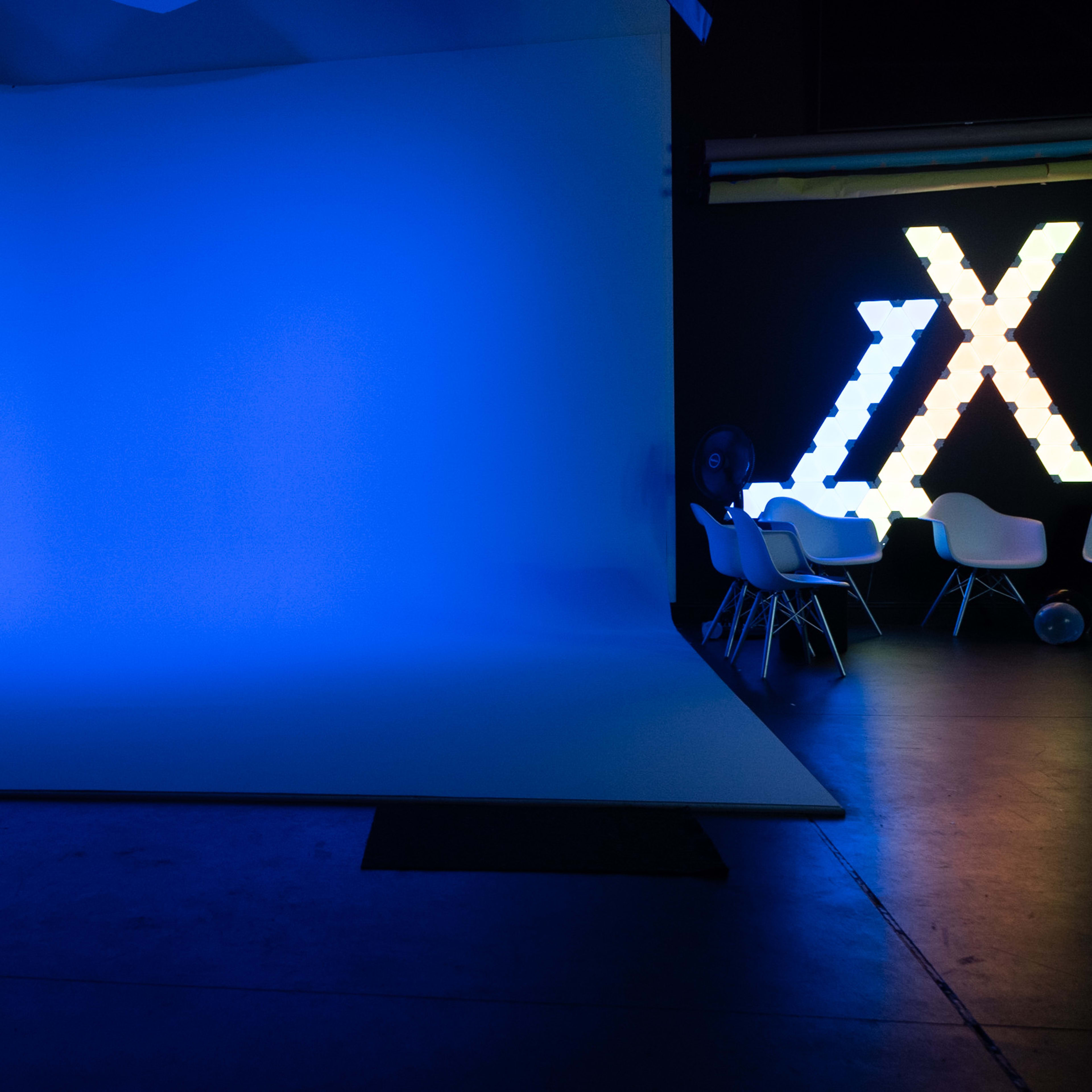 A dimly lit studio with a blue backdrop and illuminated decorative letters on one side.
