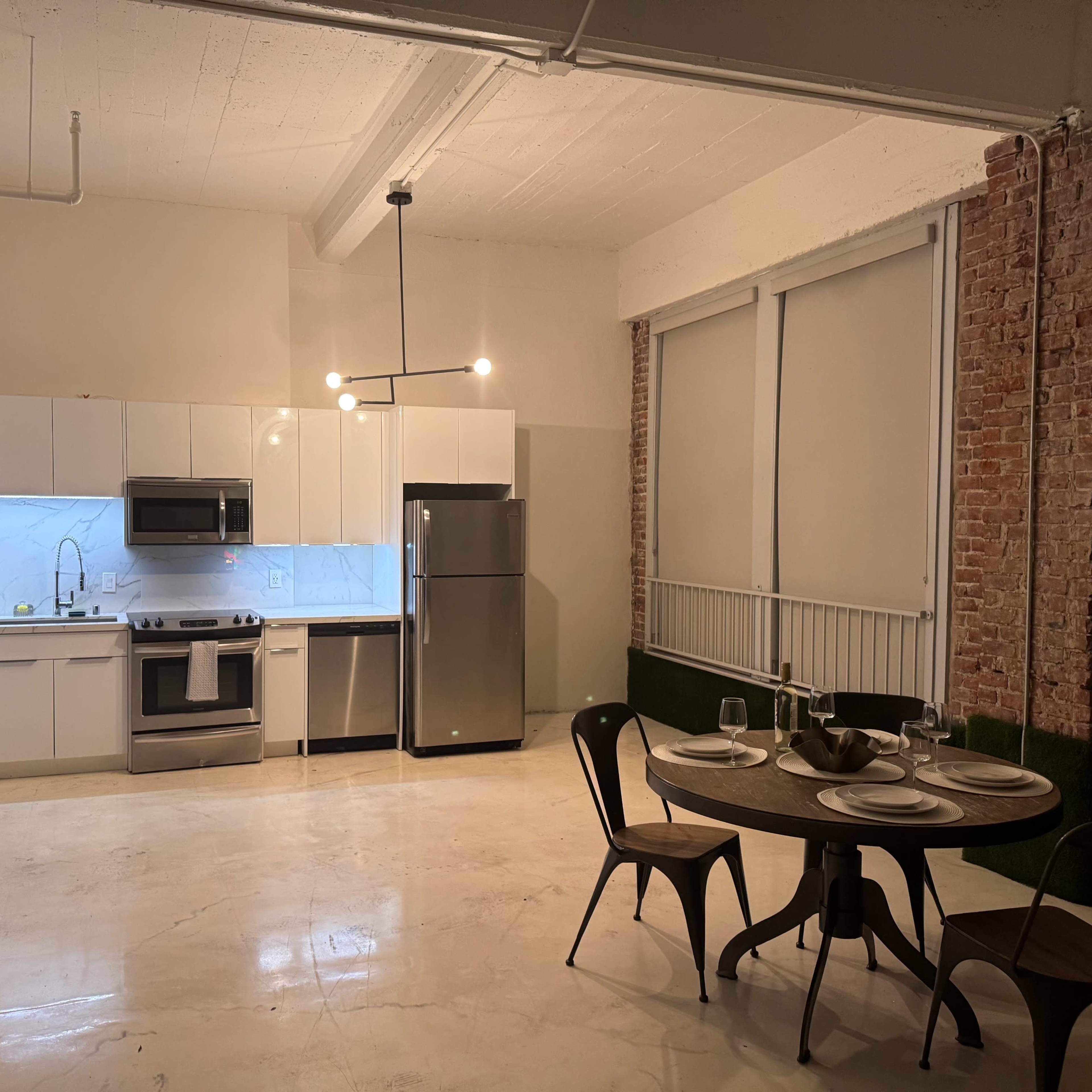 A modern kitchen with white cabinetry and stainless steel appliances, paired with a dining area featuring a round table and chairs.