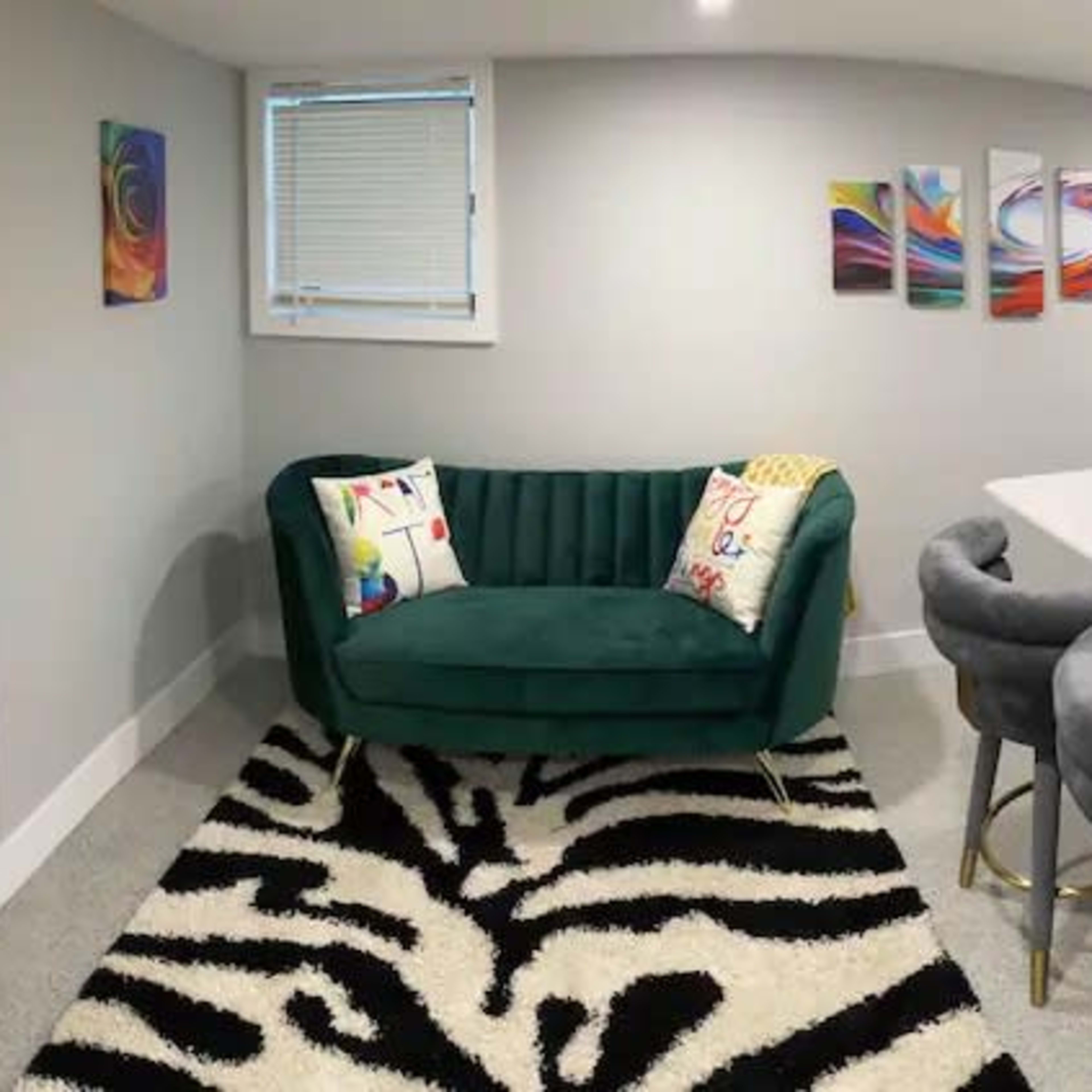 A modern kitchen and living area with a green sofa, a black and white striped rug, and sleek gray cabinetry.