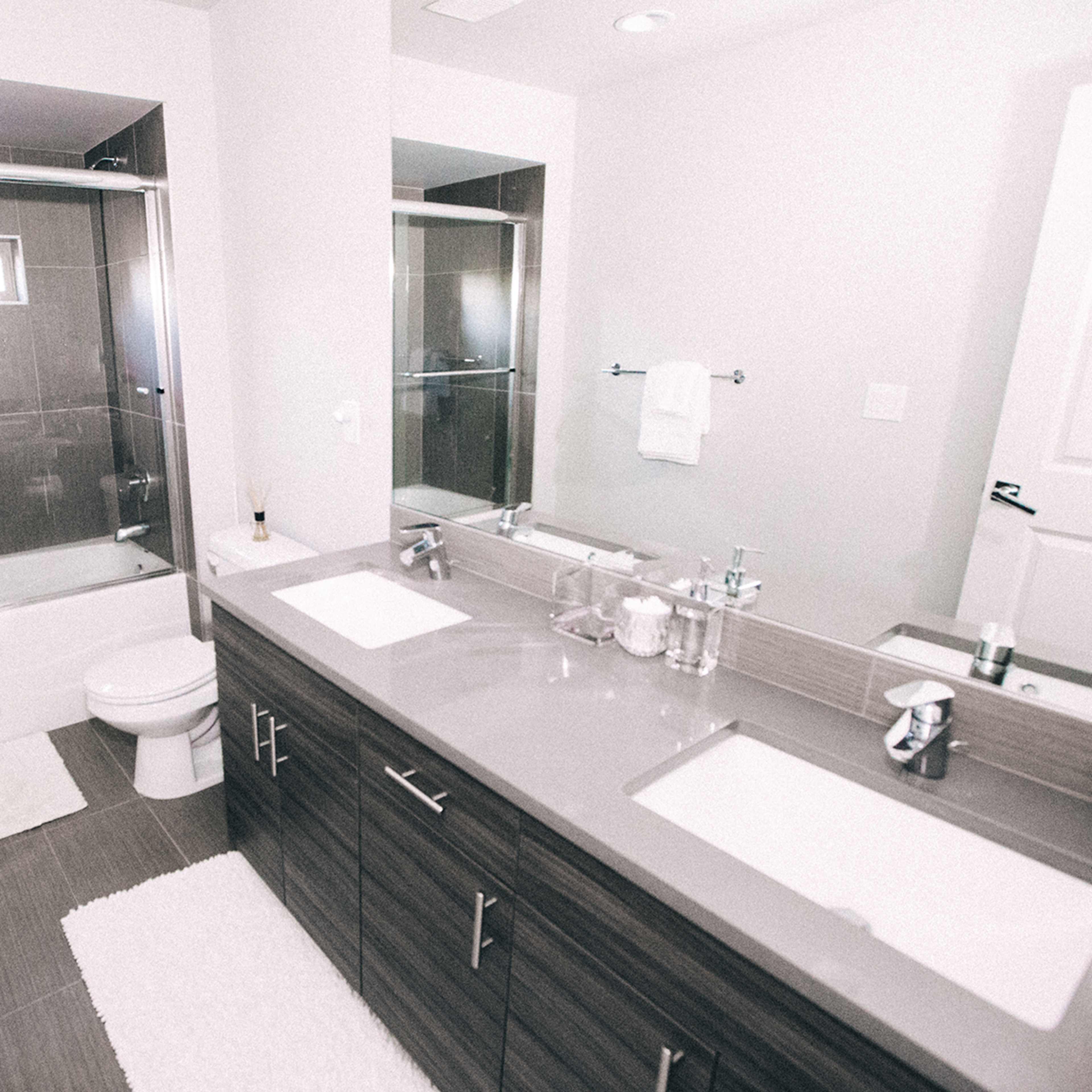 A modern bathroom with a bathtub and shower setup, dual sinks, and a clean, organized countertop.