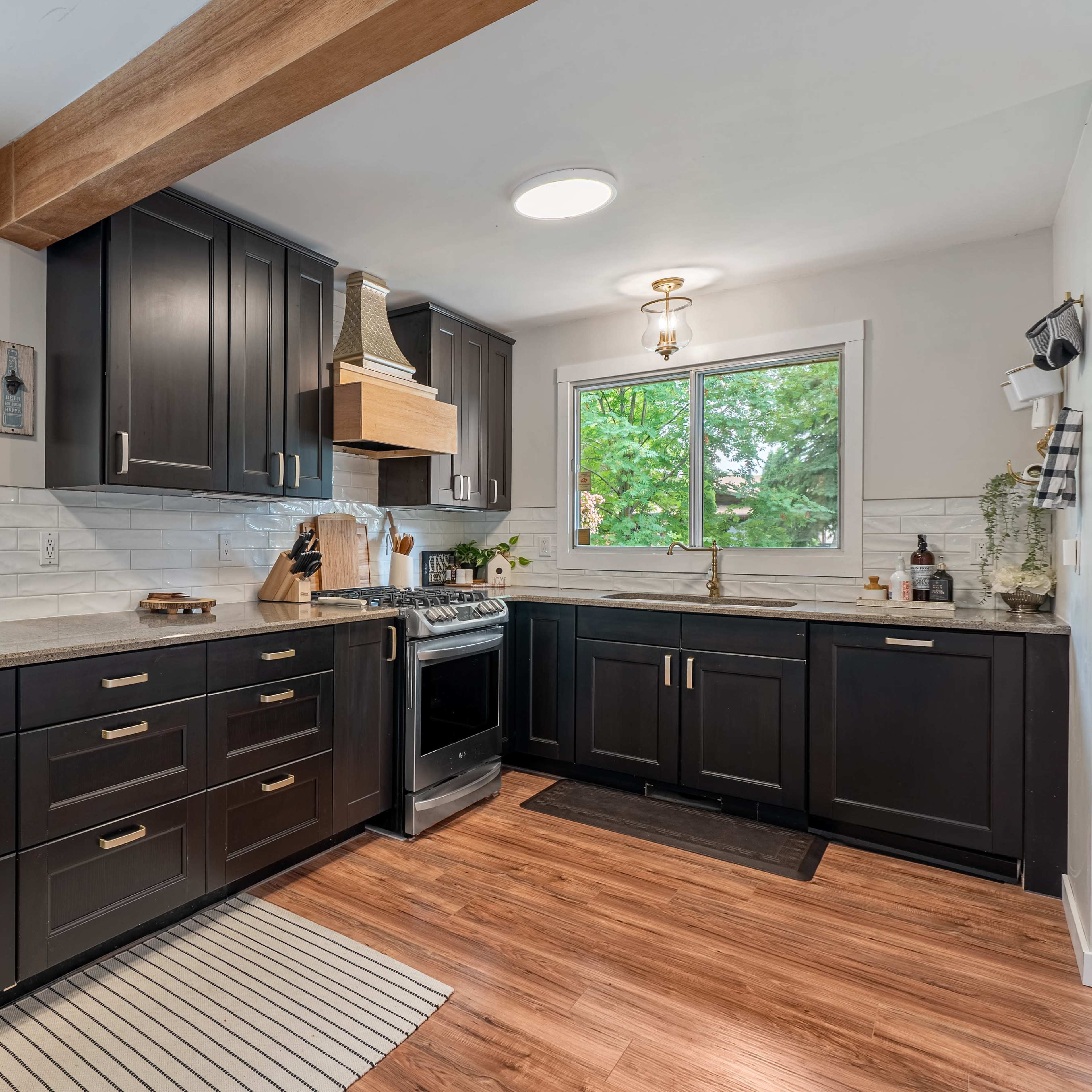 The kitchen features dark cabinetry, a central island, and large windows that offer natural light.