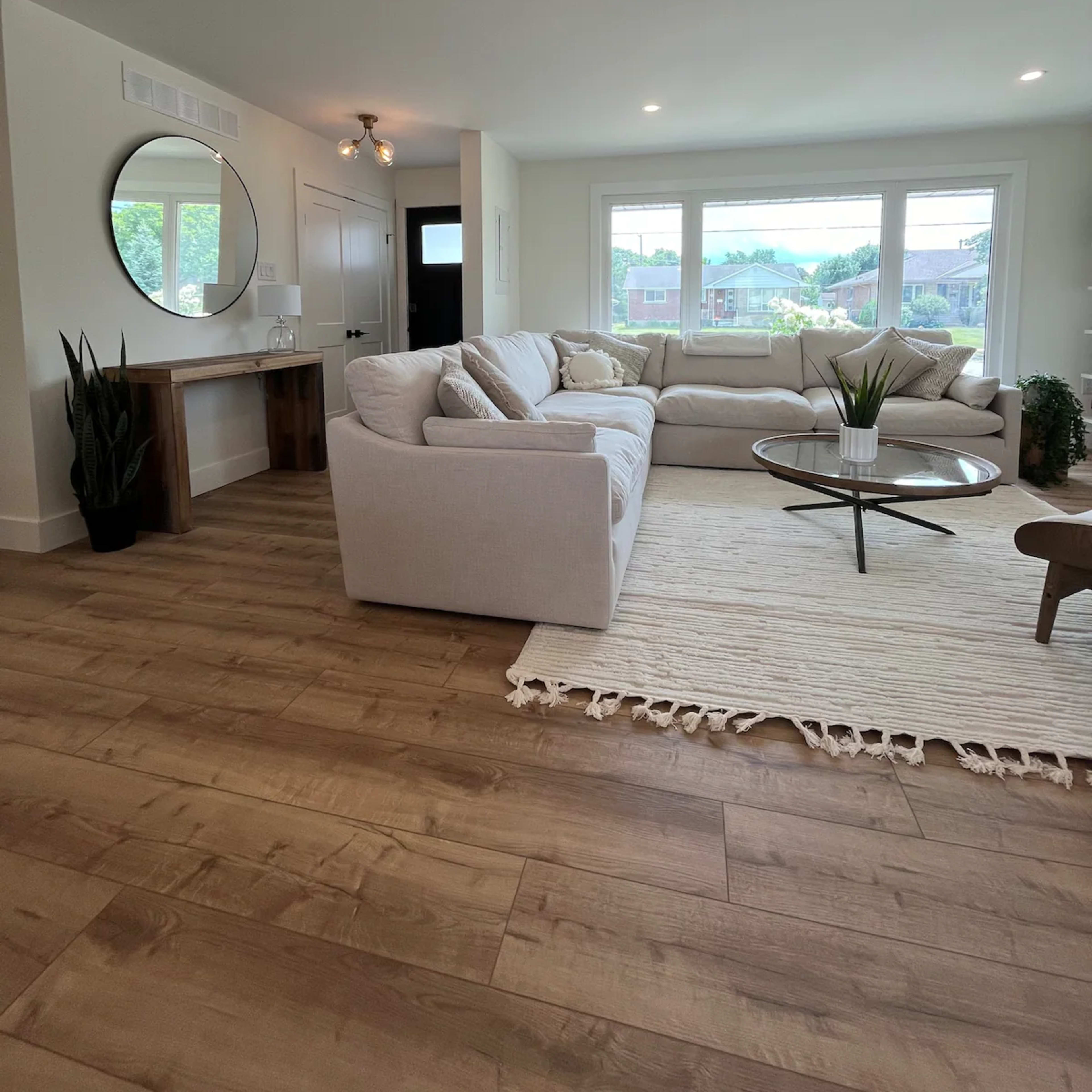 A modern living room featuring a large sectional sofa, a circular coffee table, and natural light coming through large windows.