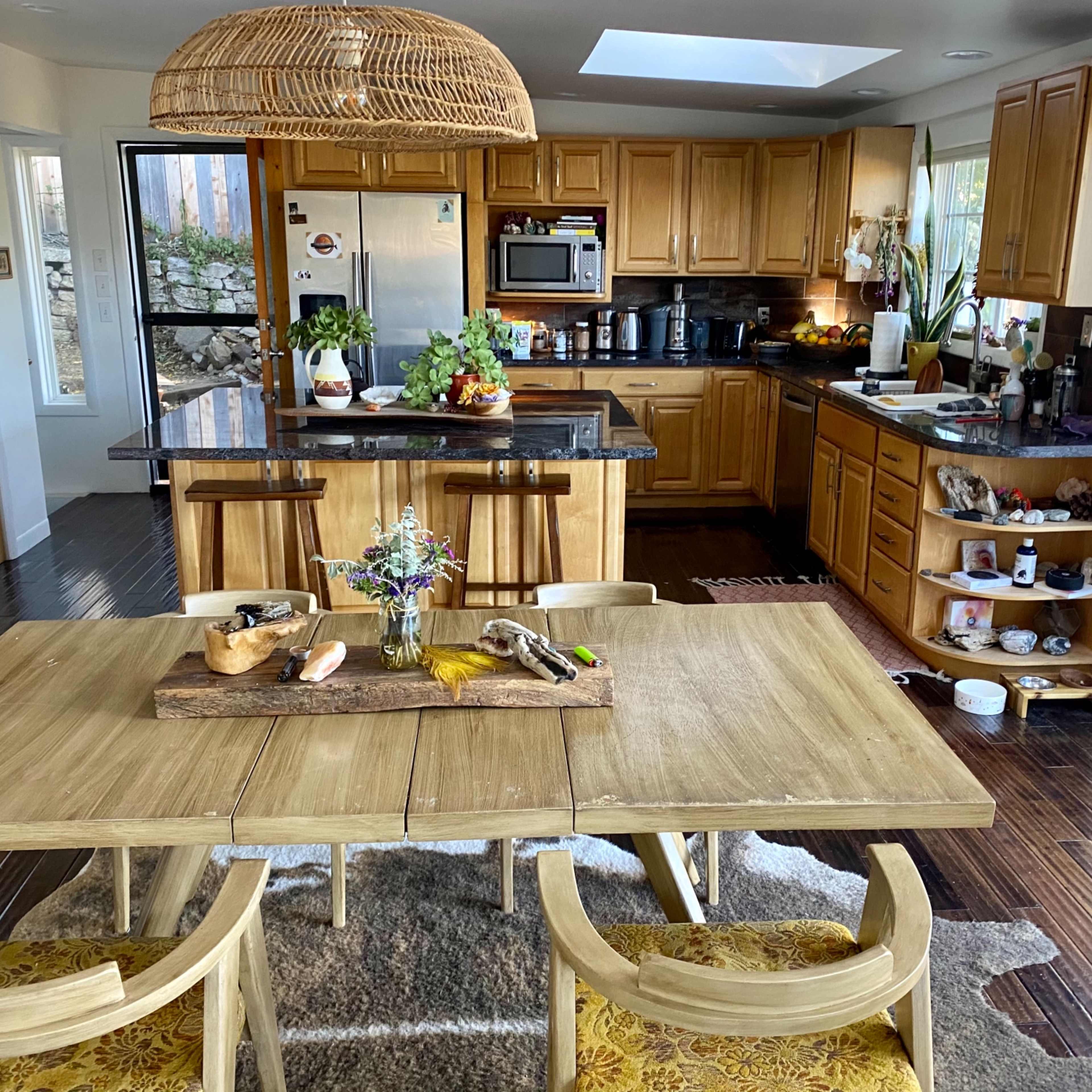 A well-lit kitchen and dining area featuring wooden cabinets, a large island with seating, and a table set with centerpieces.