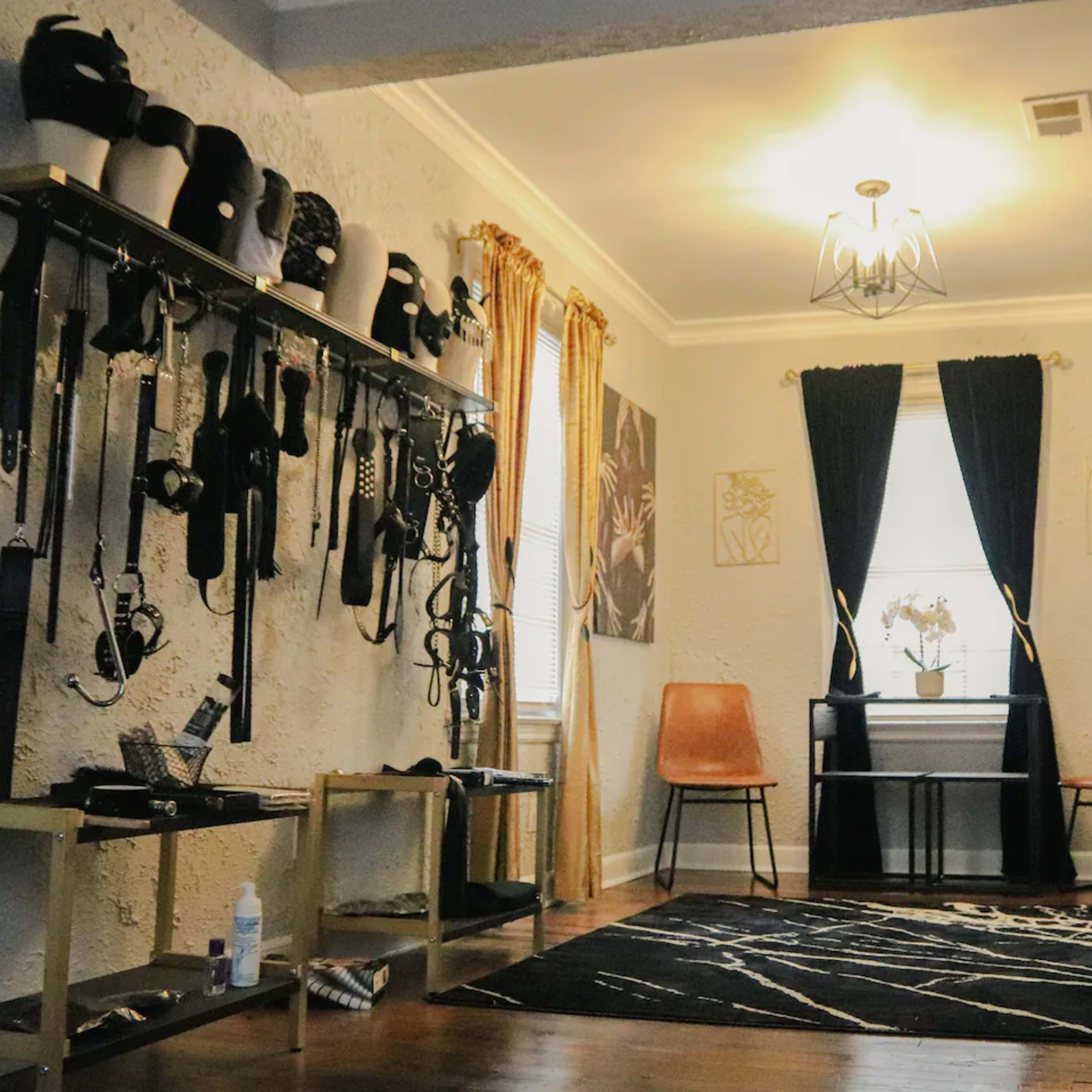 A room with a collection of harnesses and accessories displayed on racks, two chairs, and a small table with a plant in the center.