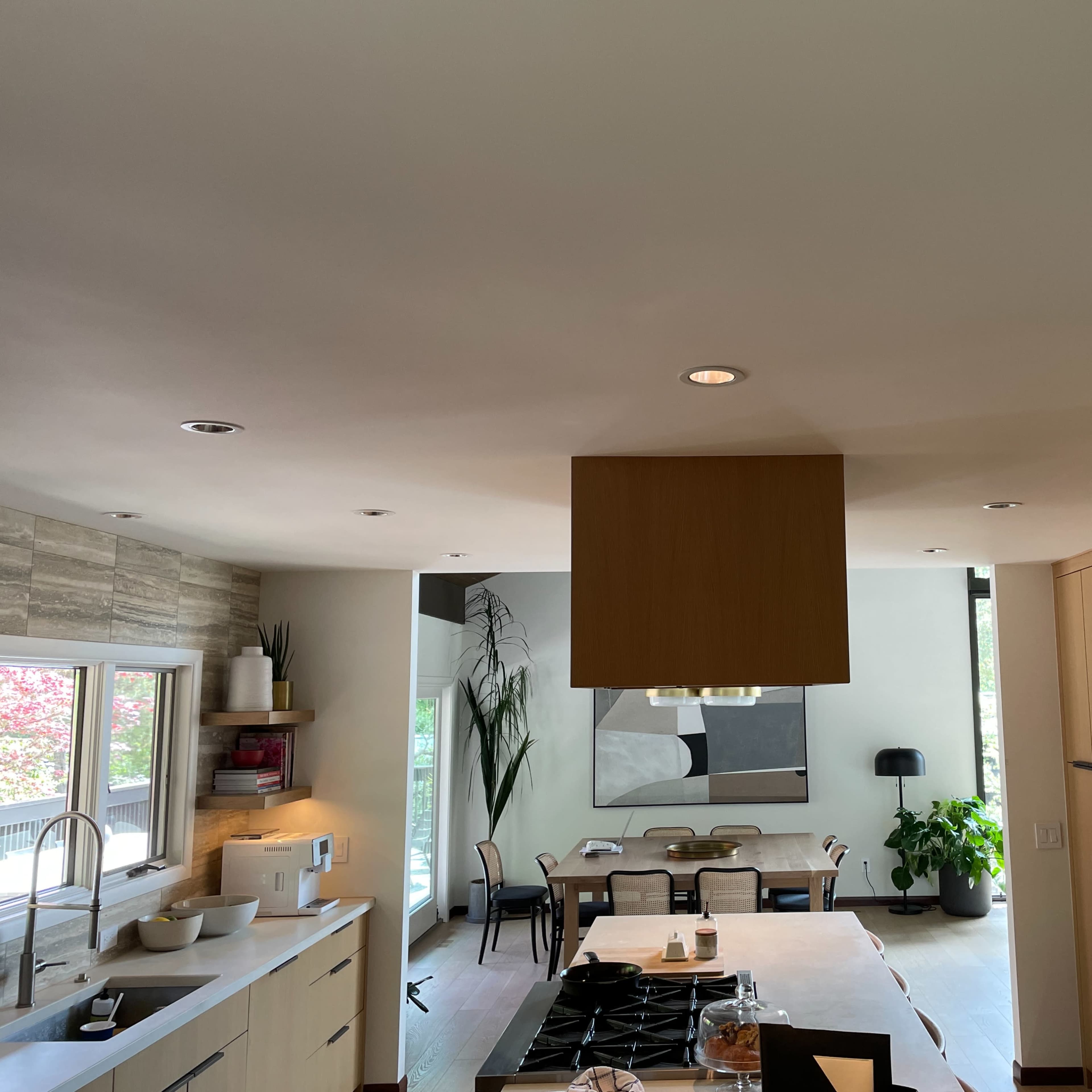 A modern kitchen with a central island, sleek cabinetry, and a dining area visible in the background.