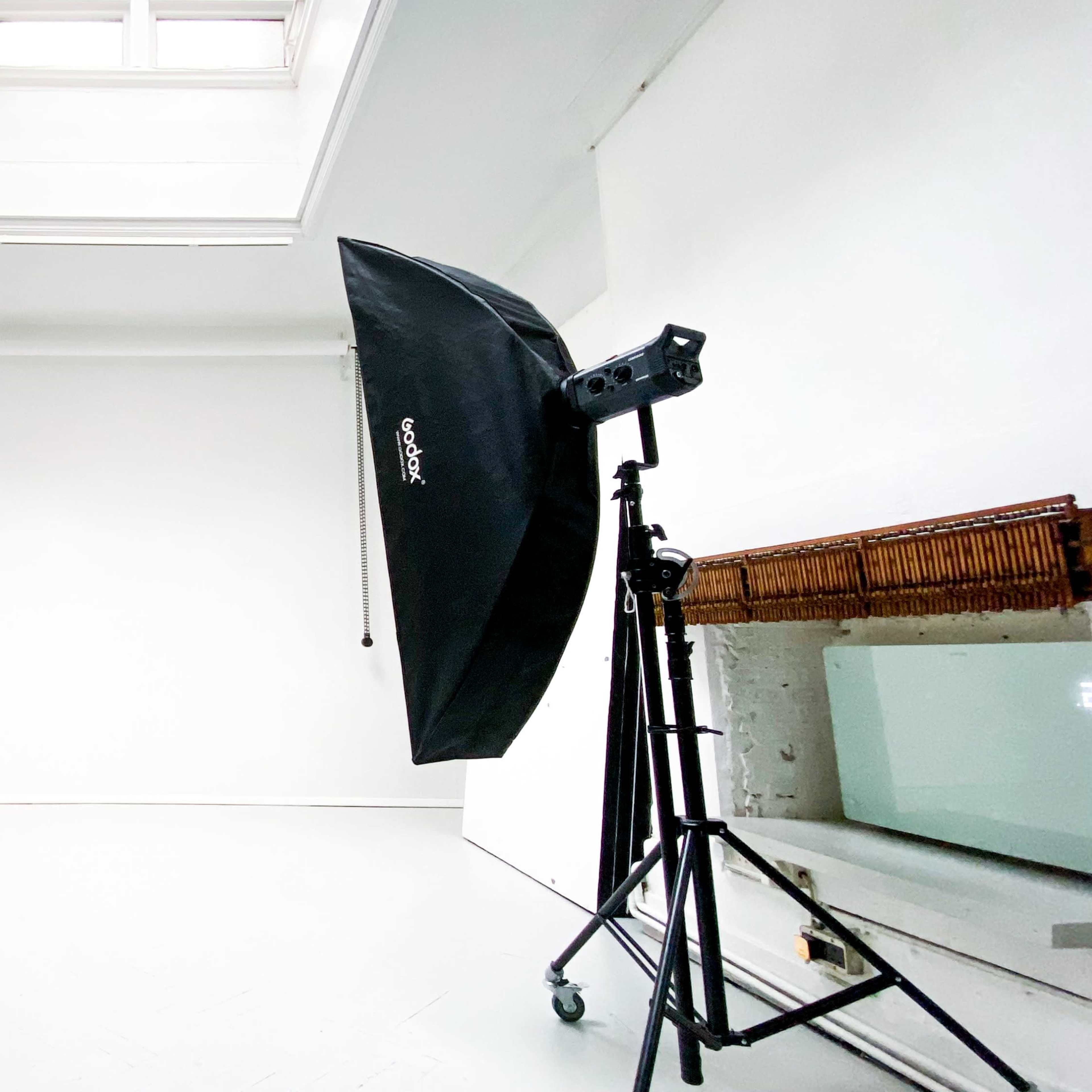 A photography studio with two large softbox lights positioned on tripods facing a plain white backdrop.