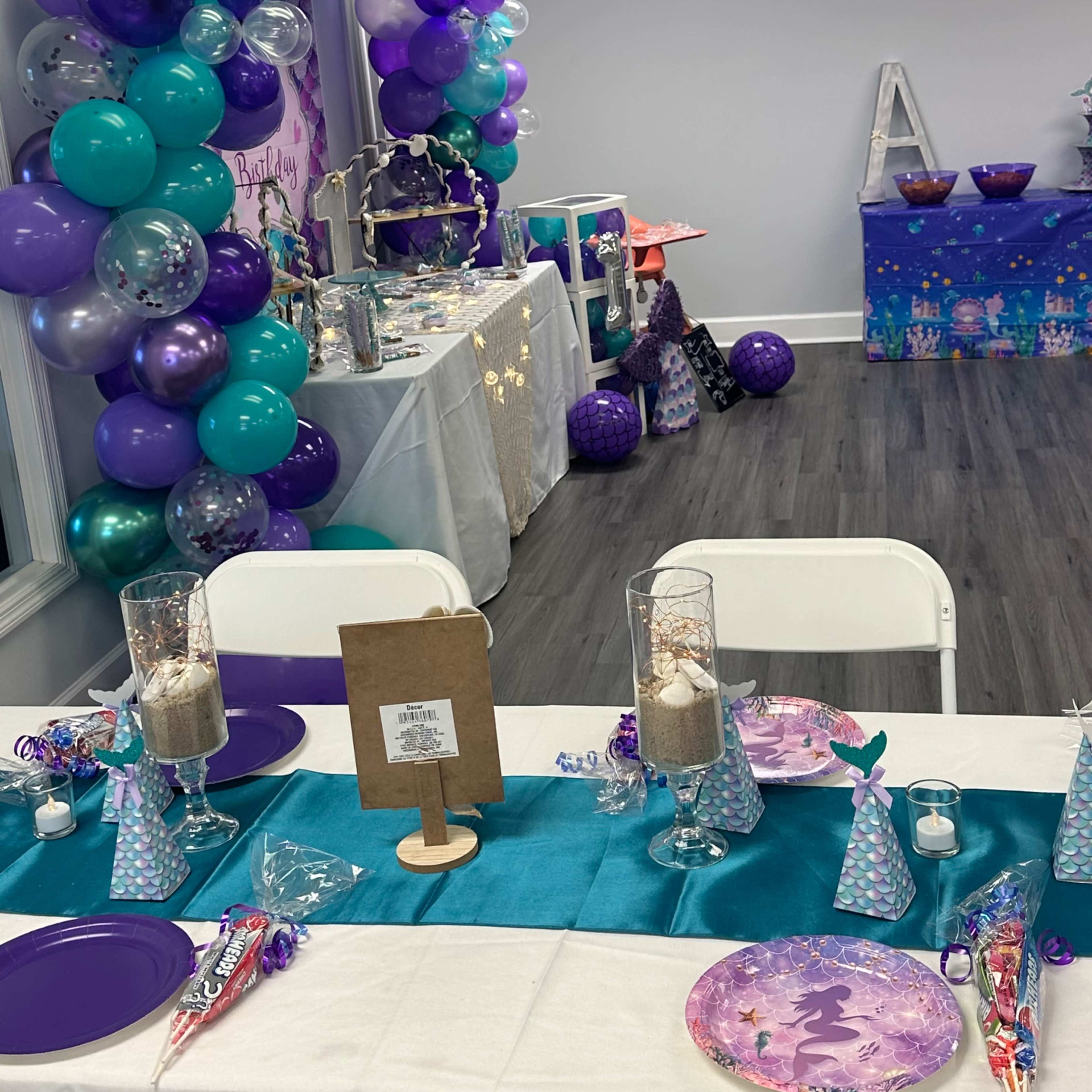 A decorated event space featuring a table set with party decorations, a colorful balloon arch, and various themed items for a celebration.
