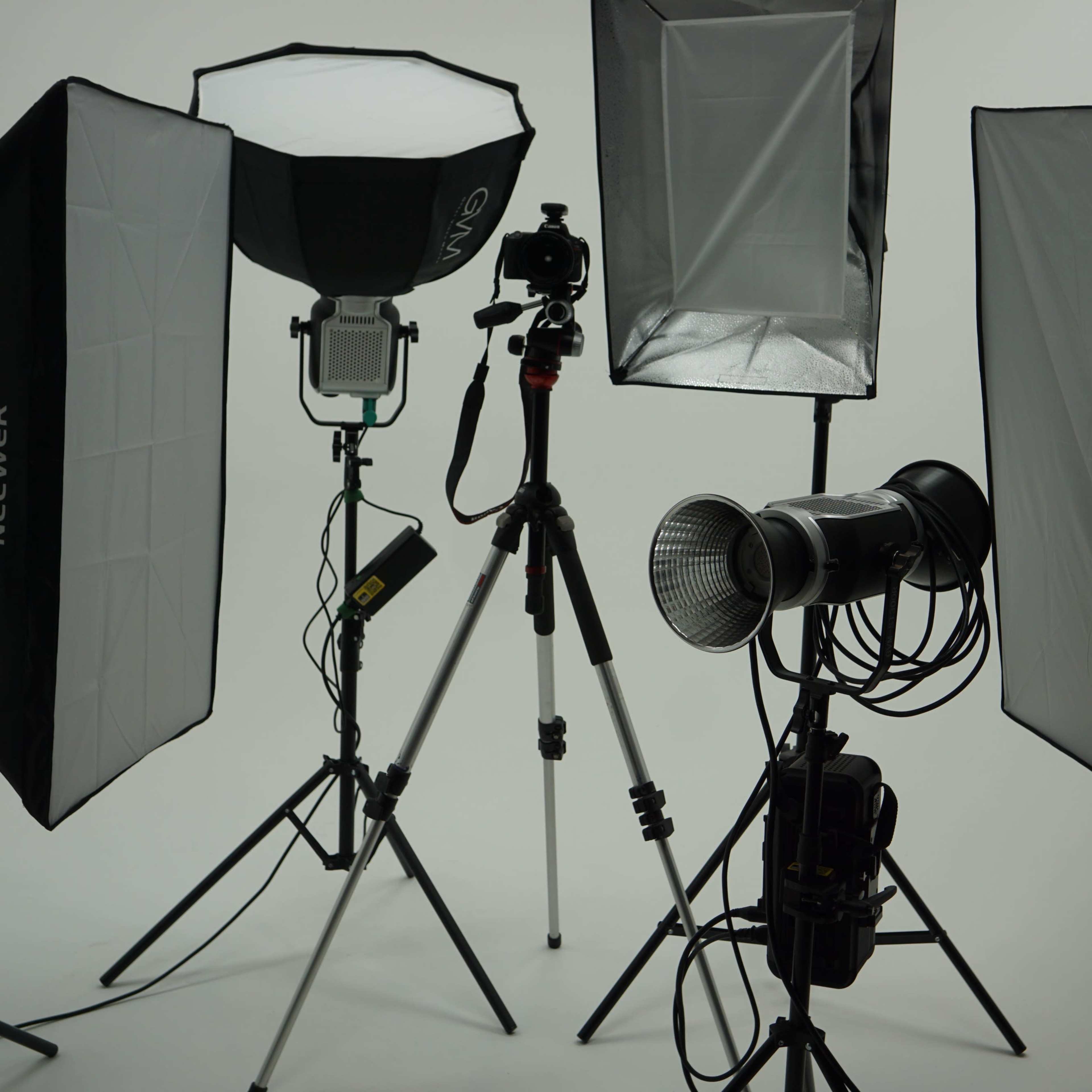 A photo studio setup with multiple softbox lights, a camera on a tripod, and a backdrop.
