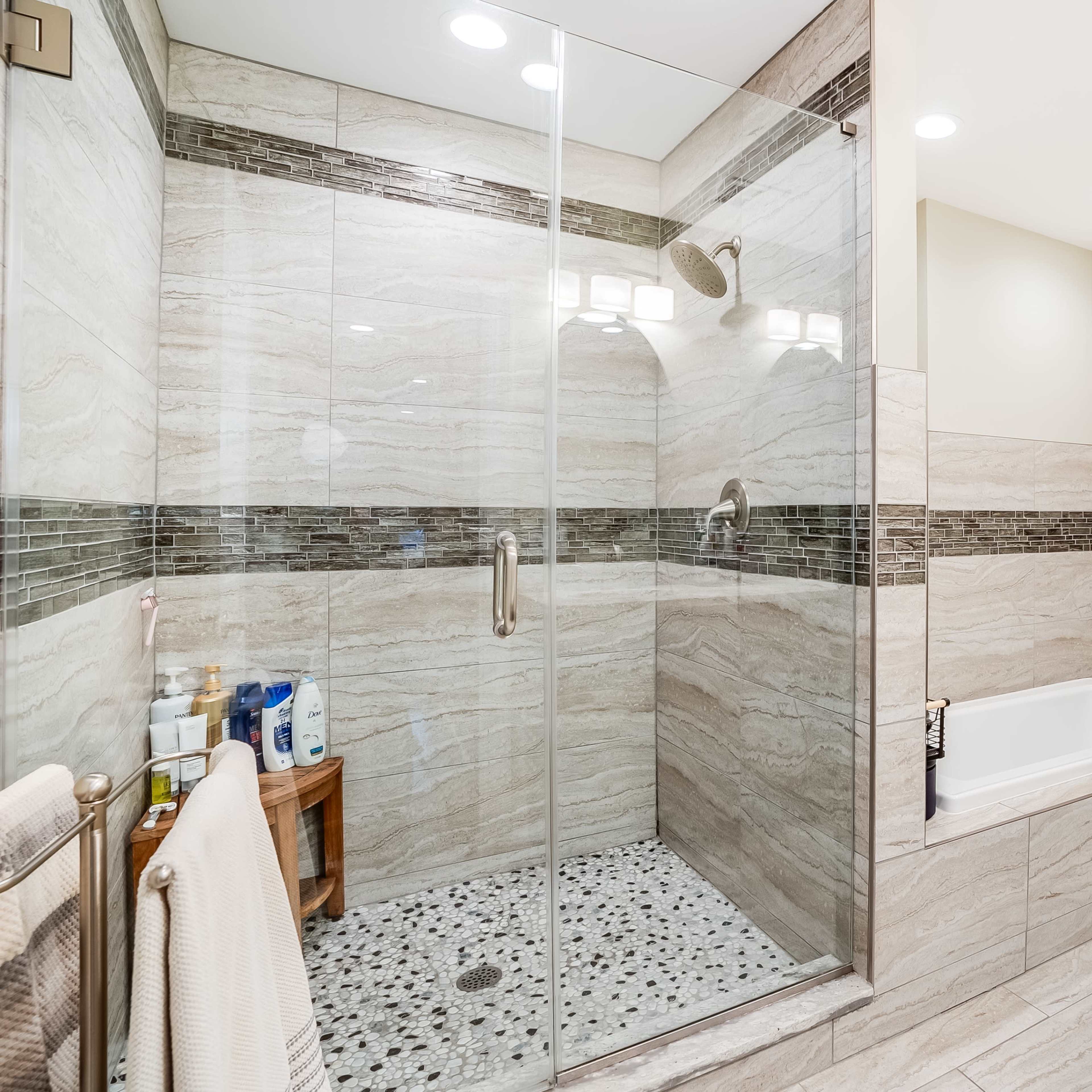 A modern bathroom featuring a glass-enclosed shower, a freestanding bathtub, and a double sink vanity with a speckled countertop.