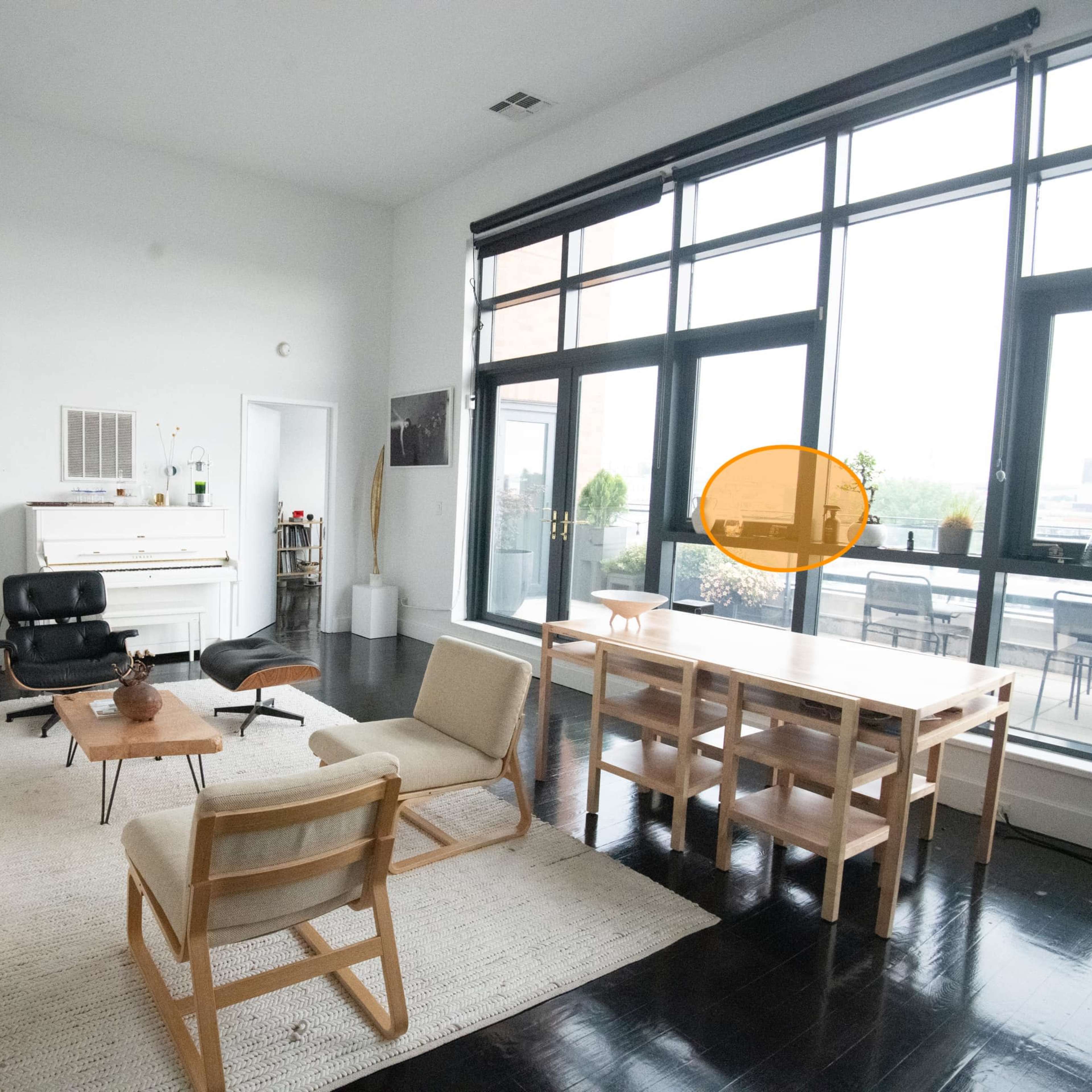 A spacious living area with a white sofa, wooden furniture, and large windows overlooking a patio.