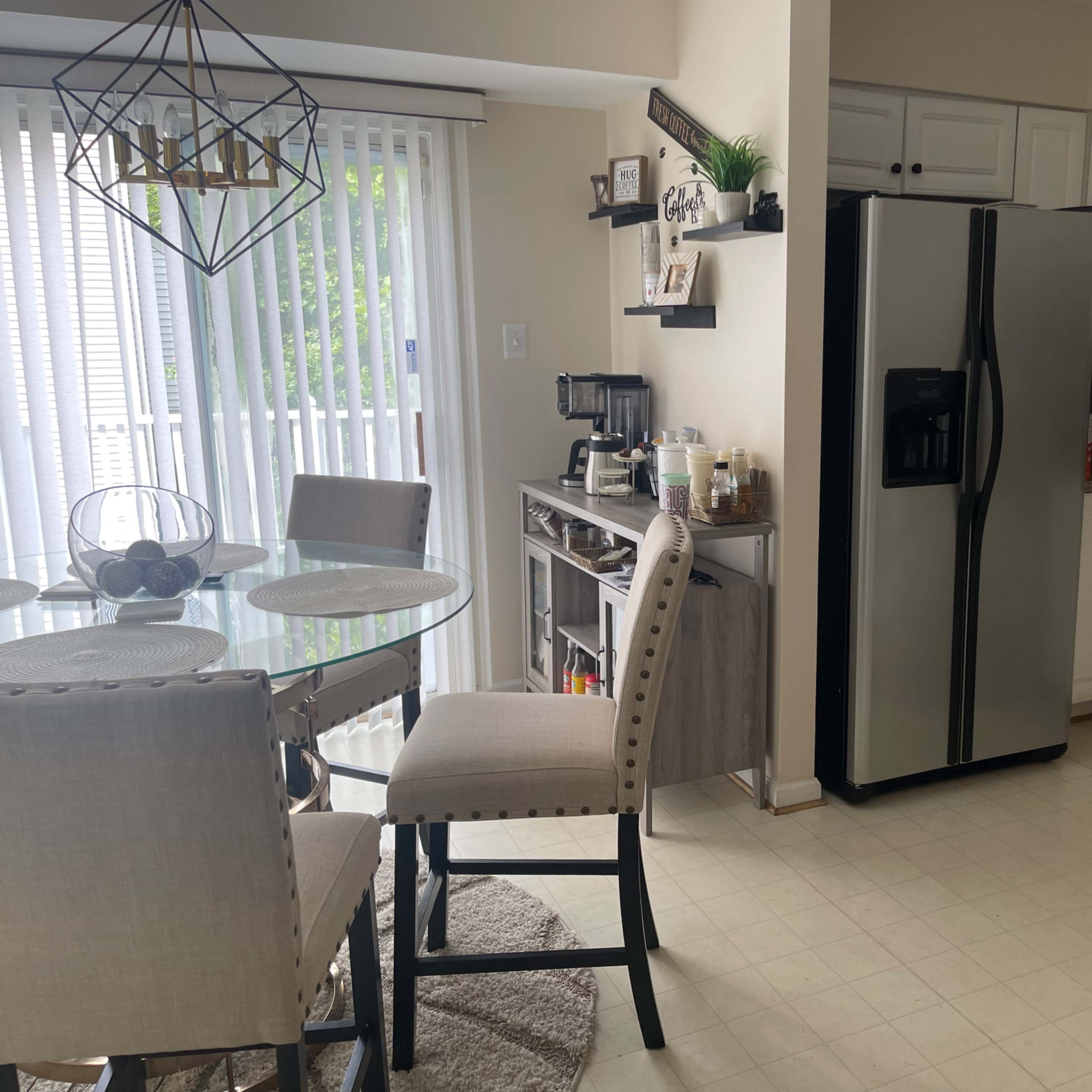 A modern kitchen with a round dining table, four upholstered chairs, and stainless steel appliances.