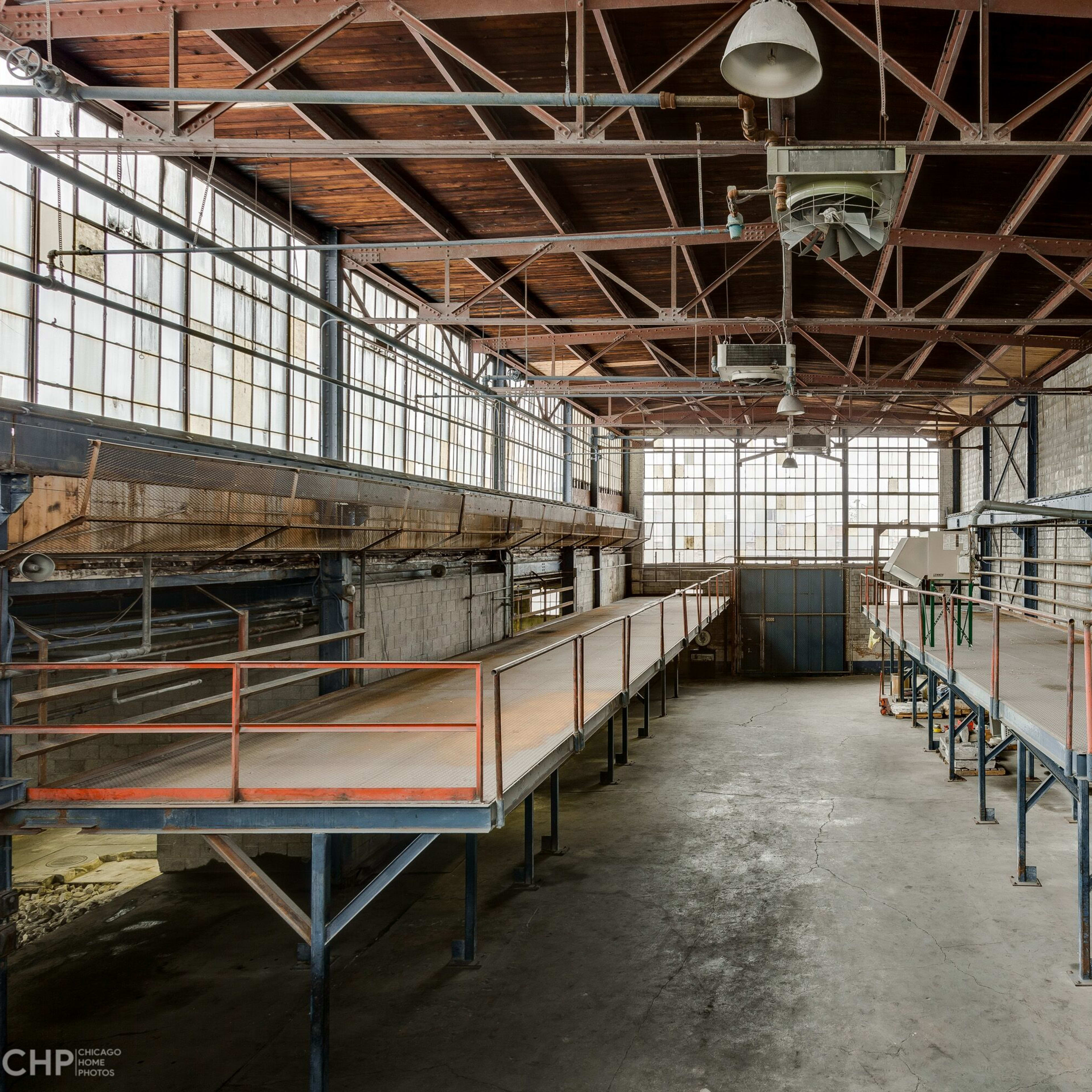 An industrial interior with metal structures and elevated platforms under large windows.