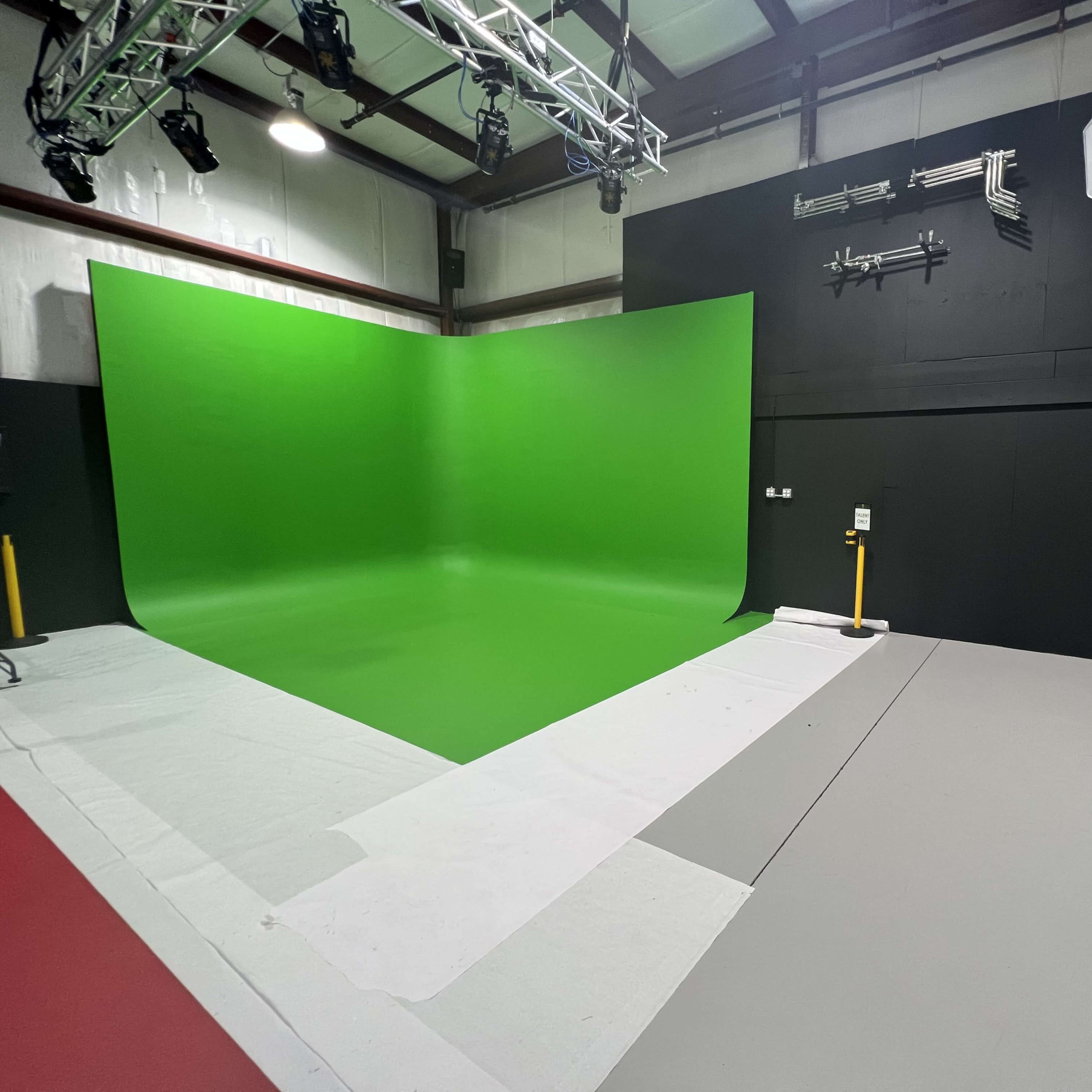 A studio setup featuring a green backdrop, lighting equipment, and a clean, organized floor space.