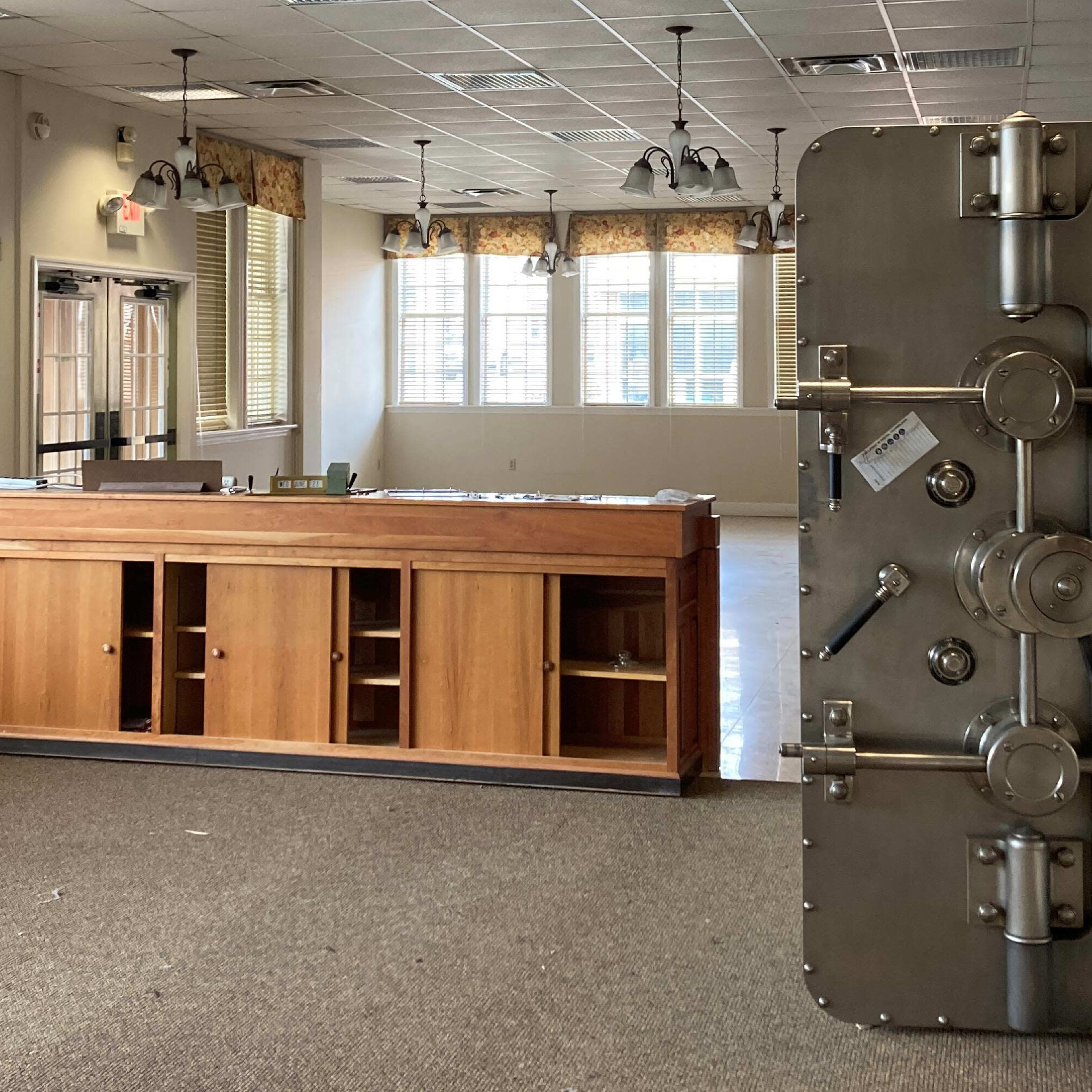 An empty room with a wooden reception desk on the left and a large metal safe on the right.