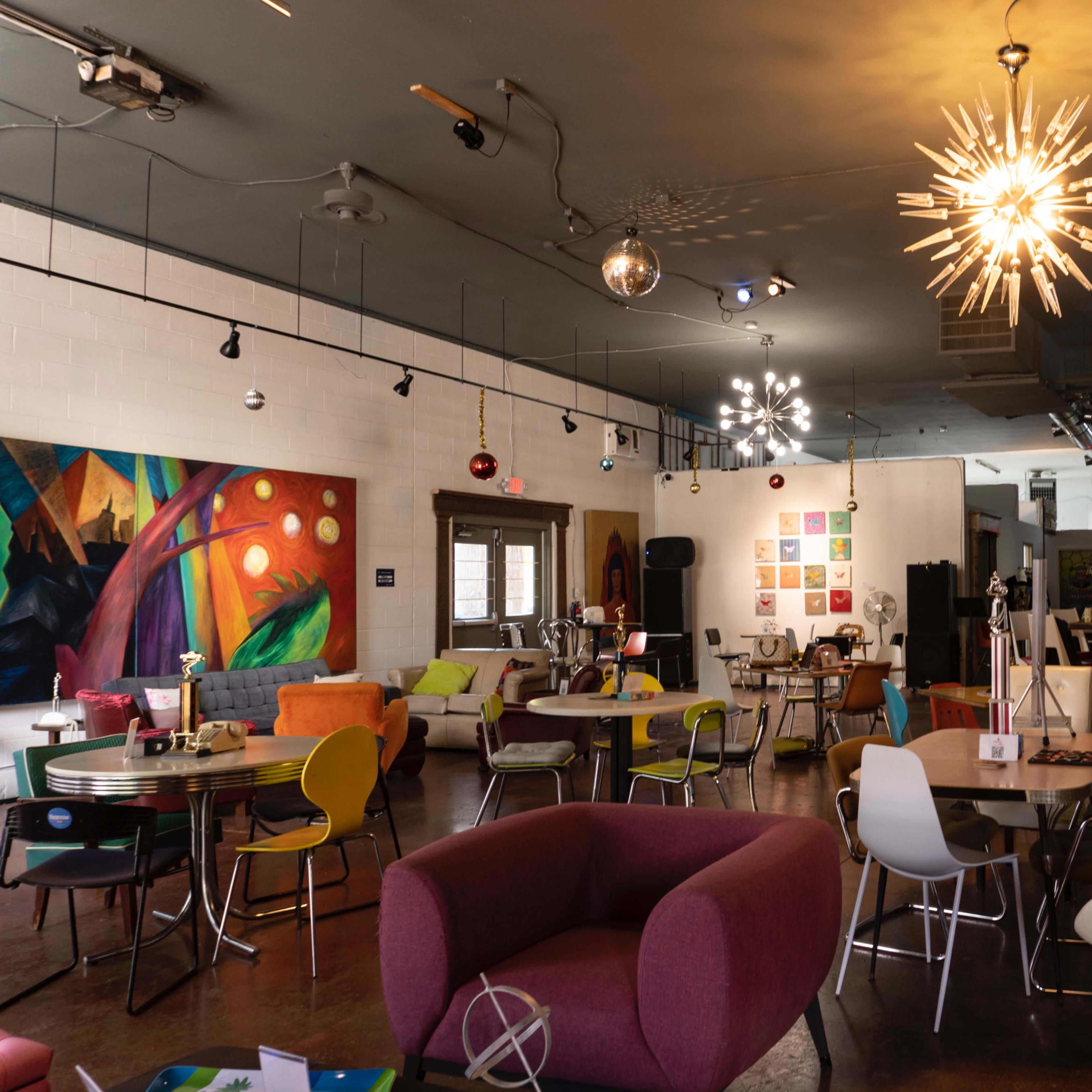 A vibrant café interior featuring colorful furniture, artistic wall decor, and unique lighting fixtures.