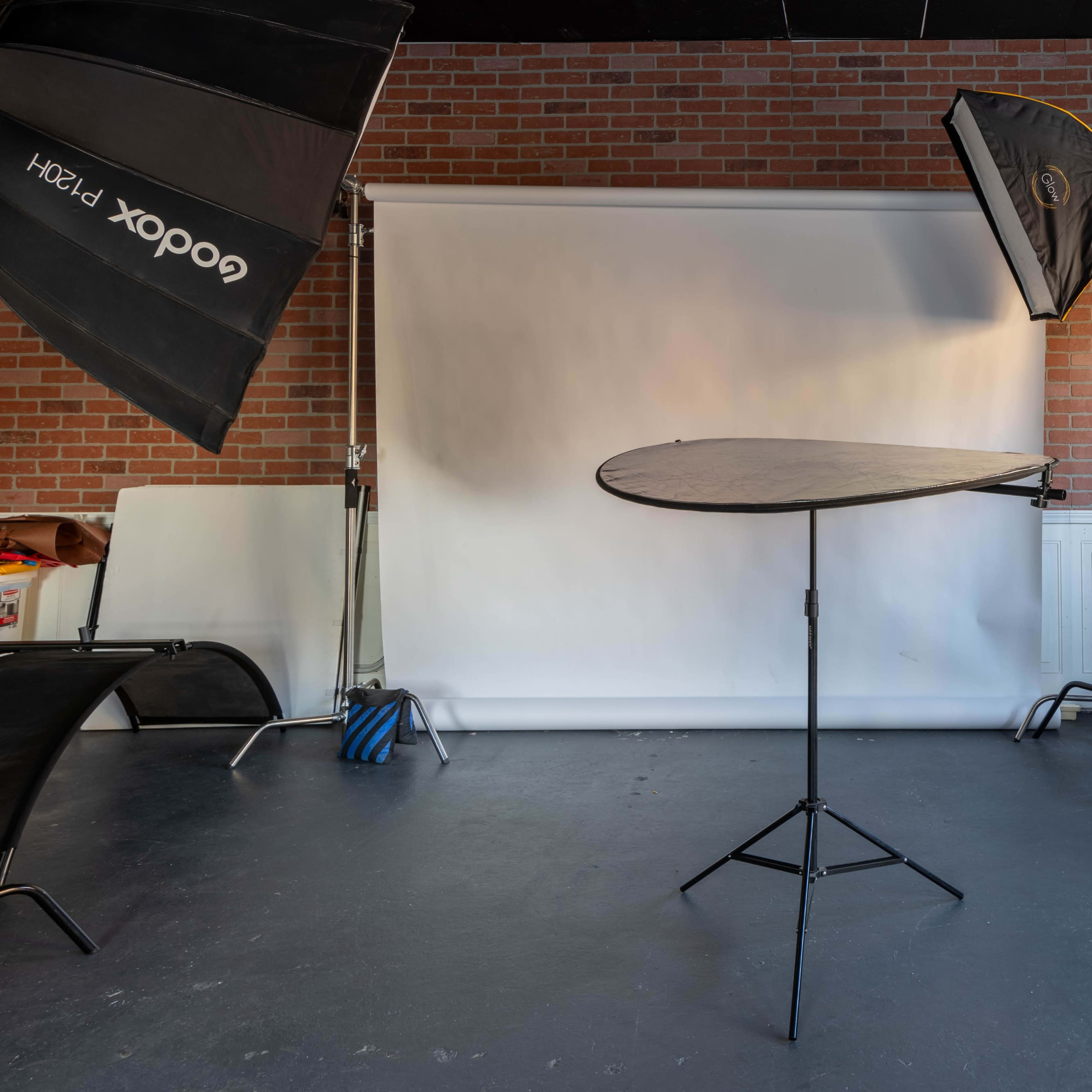 A photography studio with a seamless backdrop and three light sources set up on tripods.