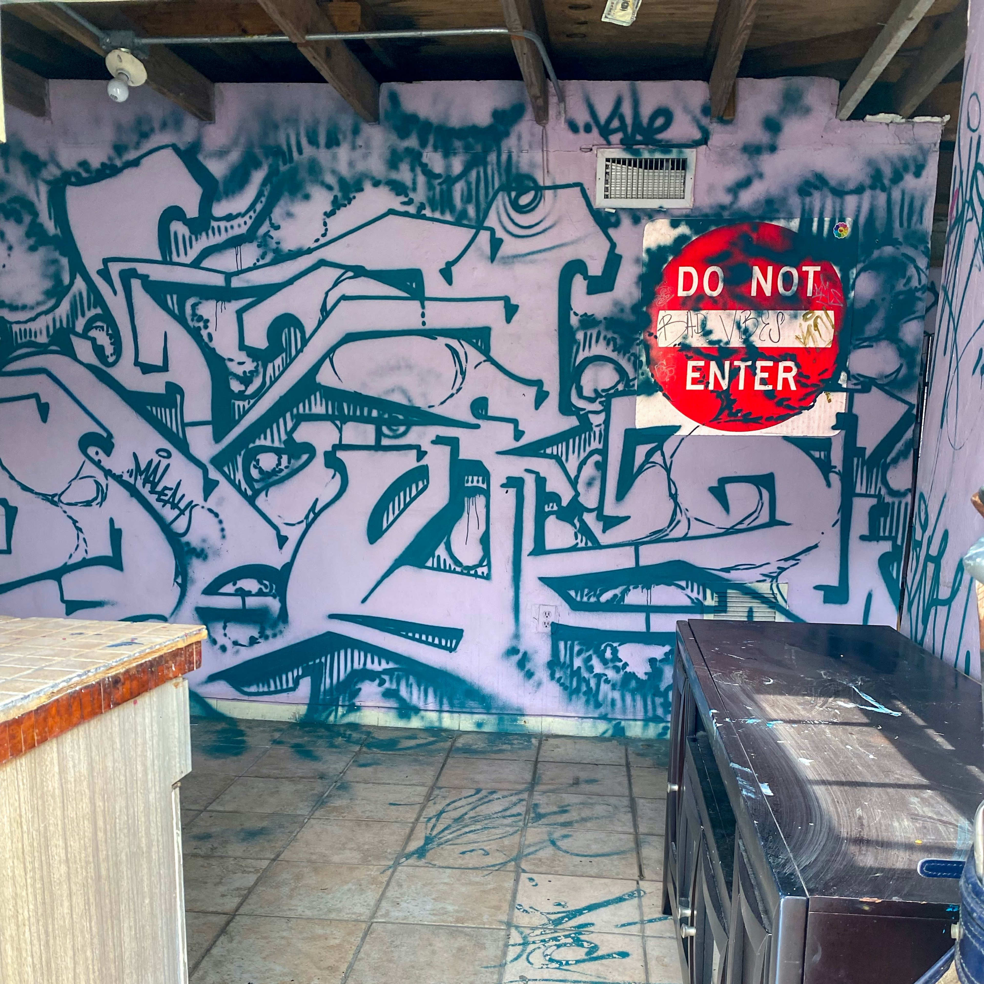 An empty room with graffiti-covered walls and a "DO NOT ENTER" sign mounted on the wall.