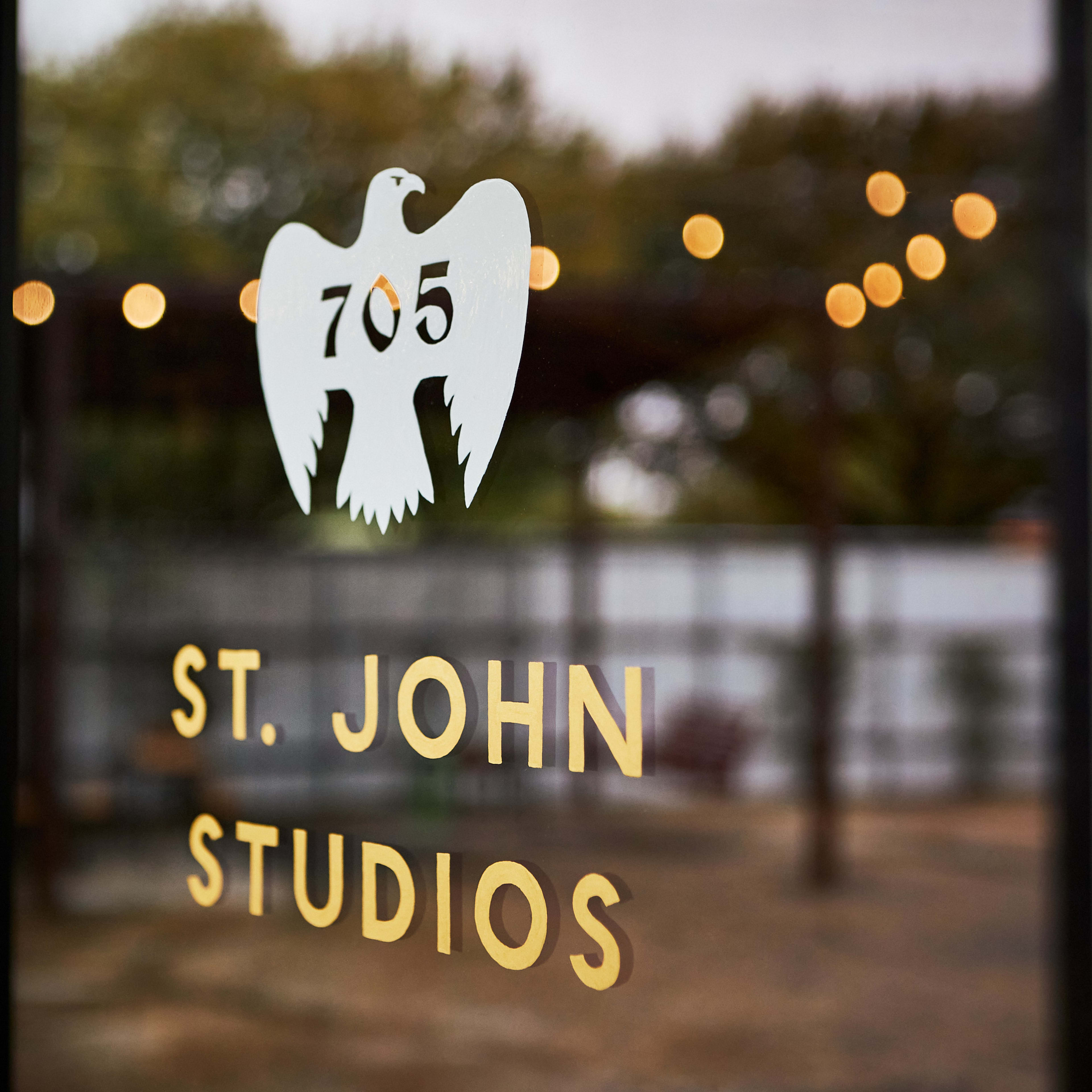 A glass door with a white eagle logo and the text "St. John Studios" in gold lettering.