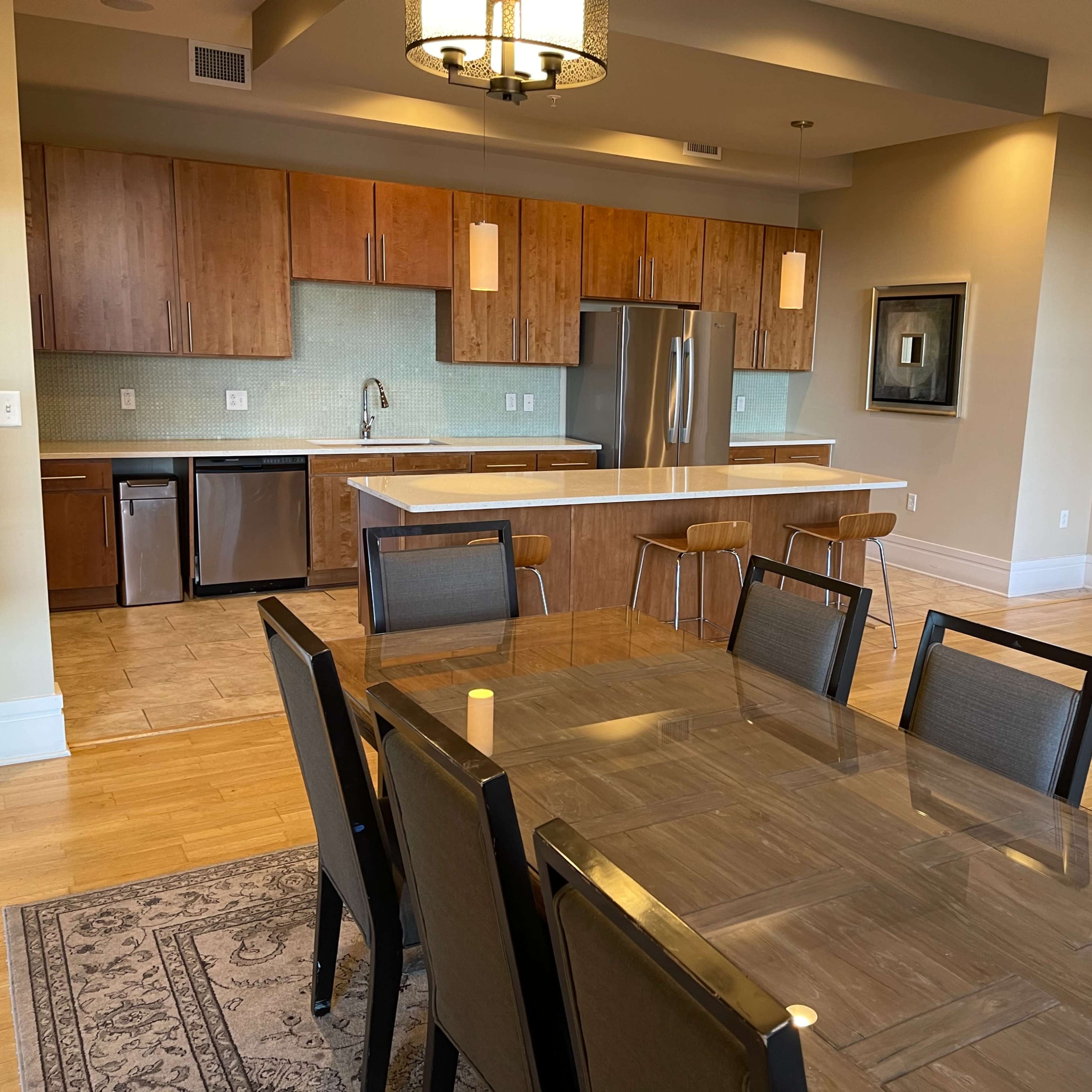 A modern kitchen and dining area featuring a large table, wooden cabinetry, and stainless steel appliances.