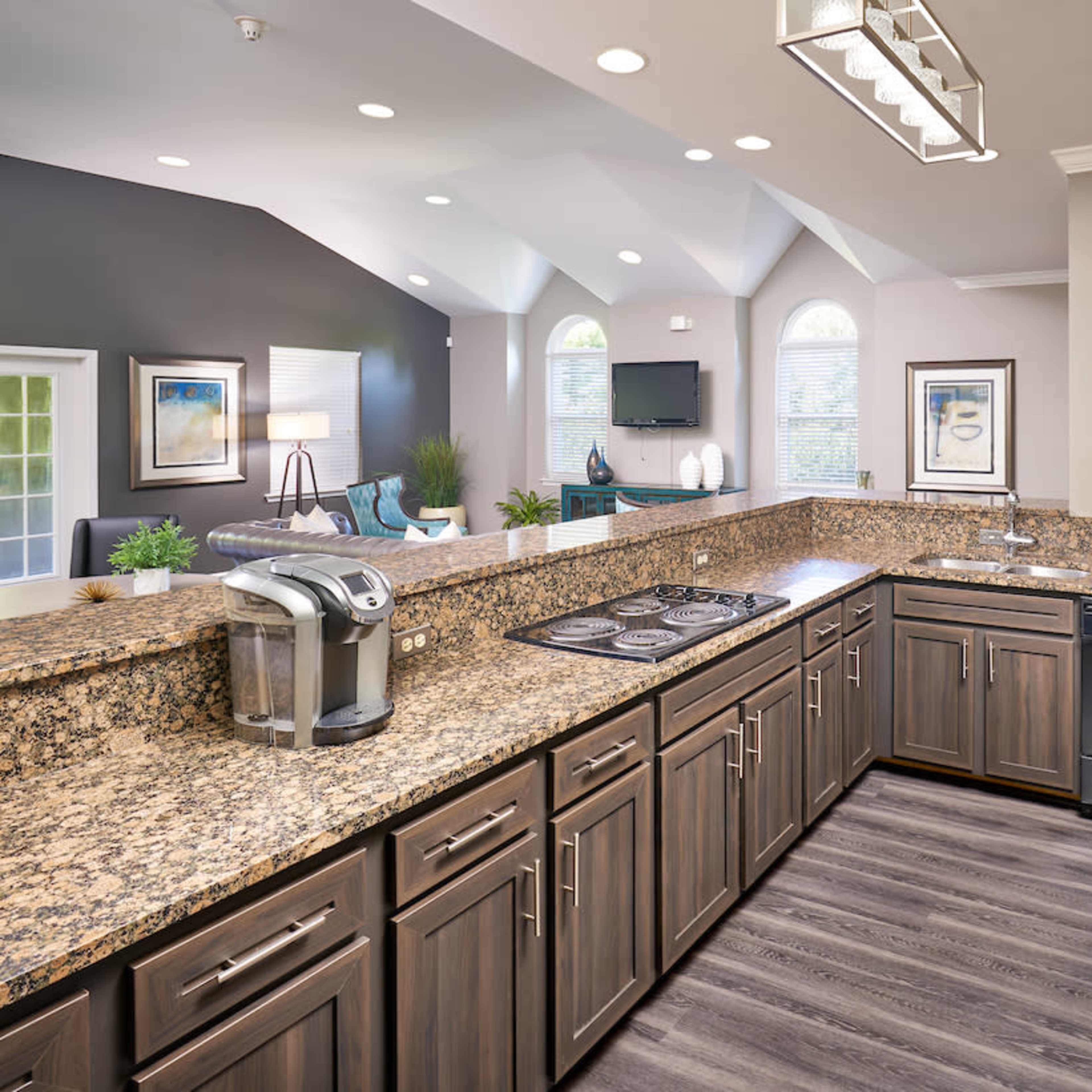 A modern kitchen featuring dark wood cabinets, a granite countertop, and built-in appliances like a microwave and a coffee maker.