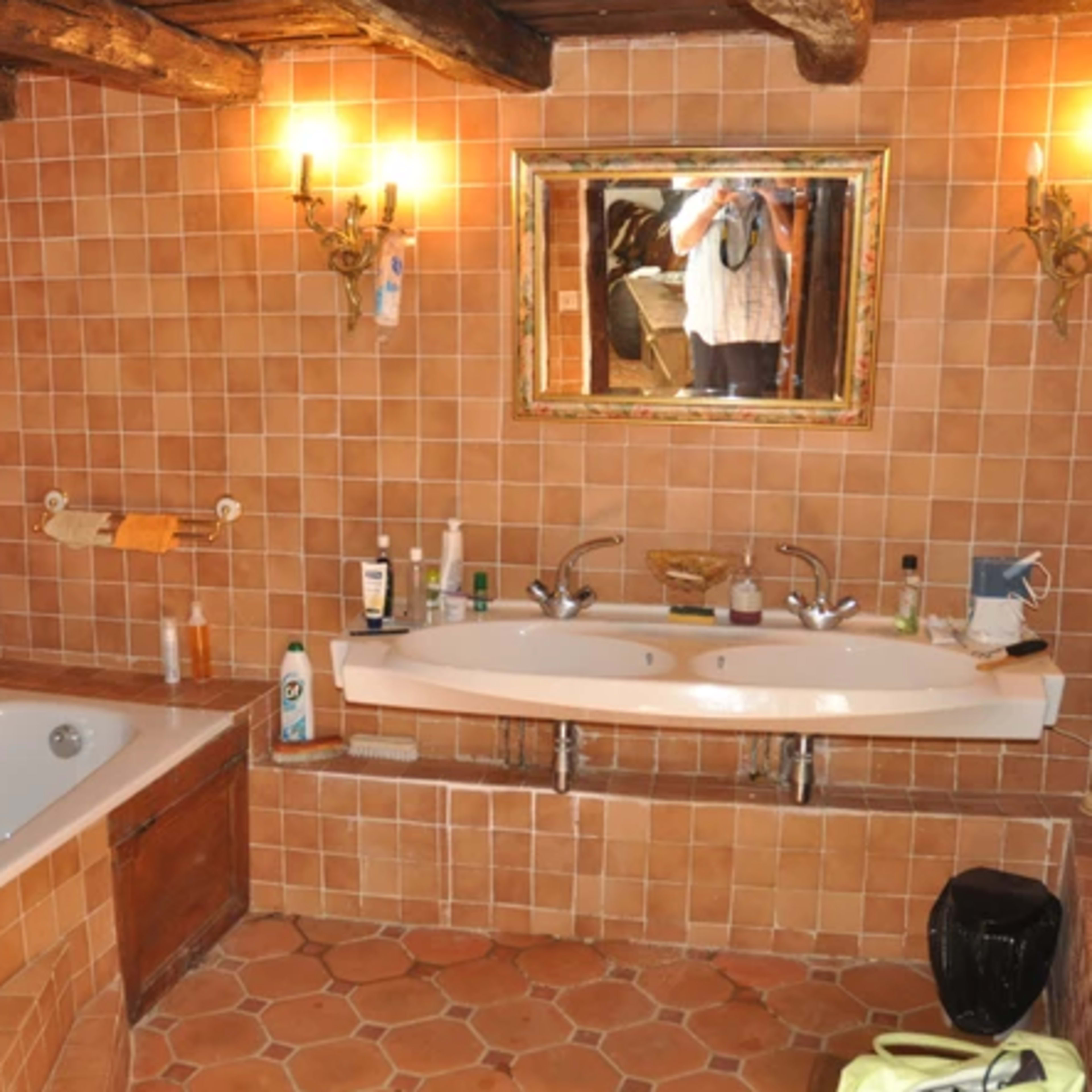 A bathroom with a bathtub and a double sink, featuring tiled walls and a large mirror.