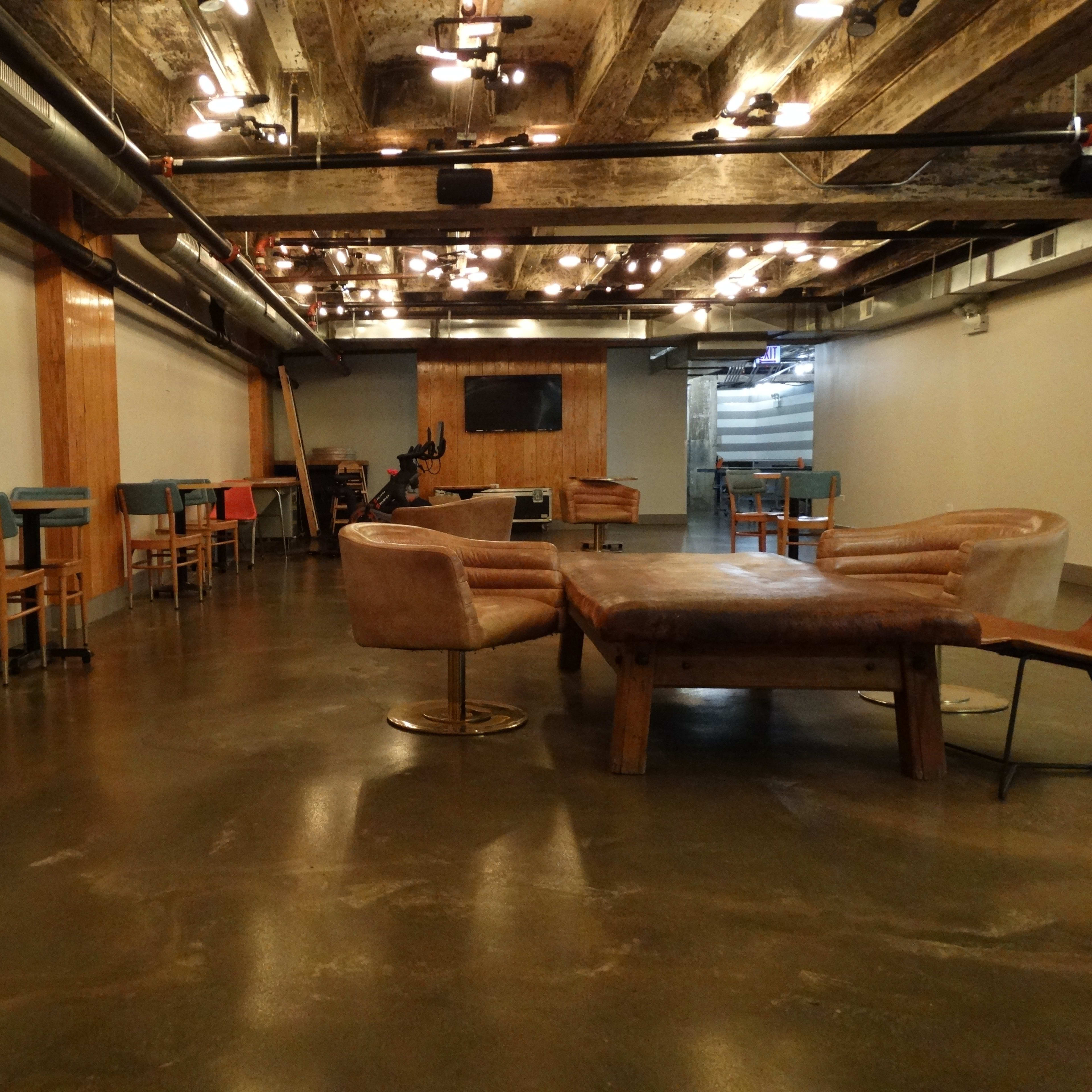A modern, industrial-style interior with wooden beams and furniture, featuring a spacious area with chairs and a large table.