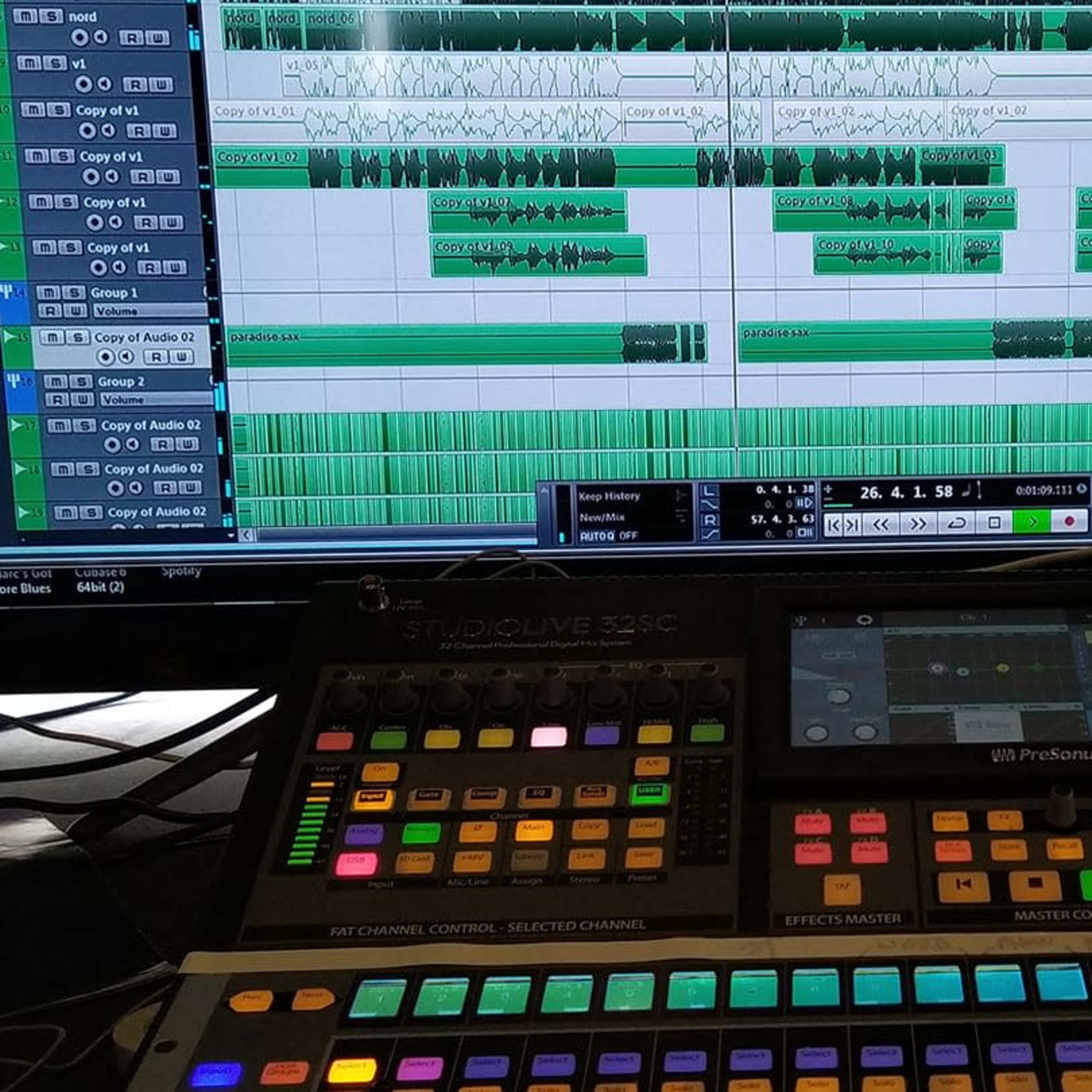 A digital audio workstation displays a music production interface with multiple tracks and audio waveforms, while a control surface with colorful buttons and sliders is positioned in the foreground.
