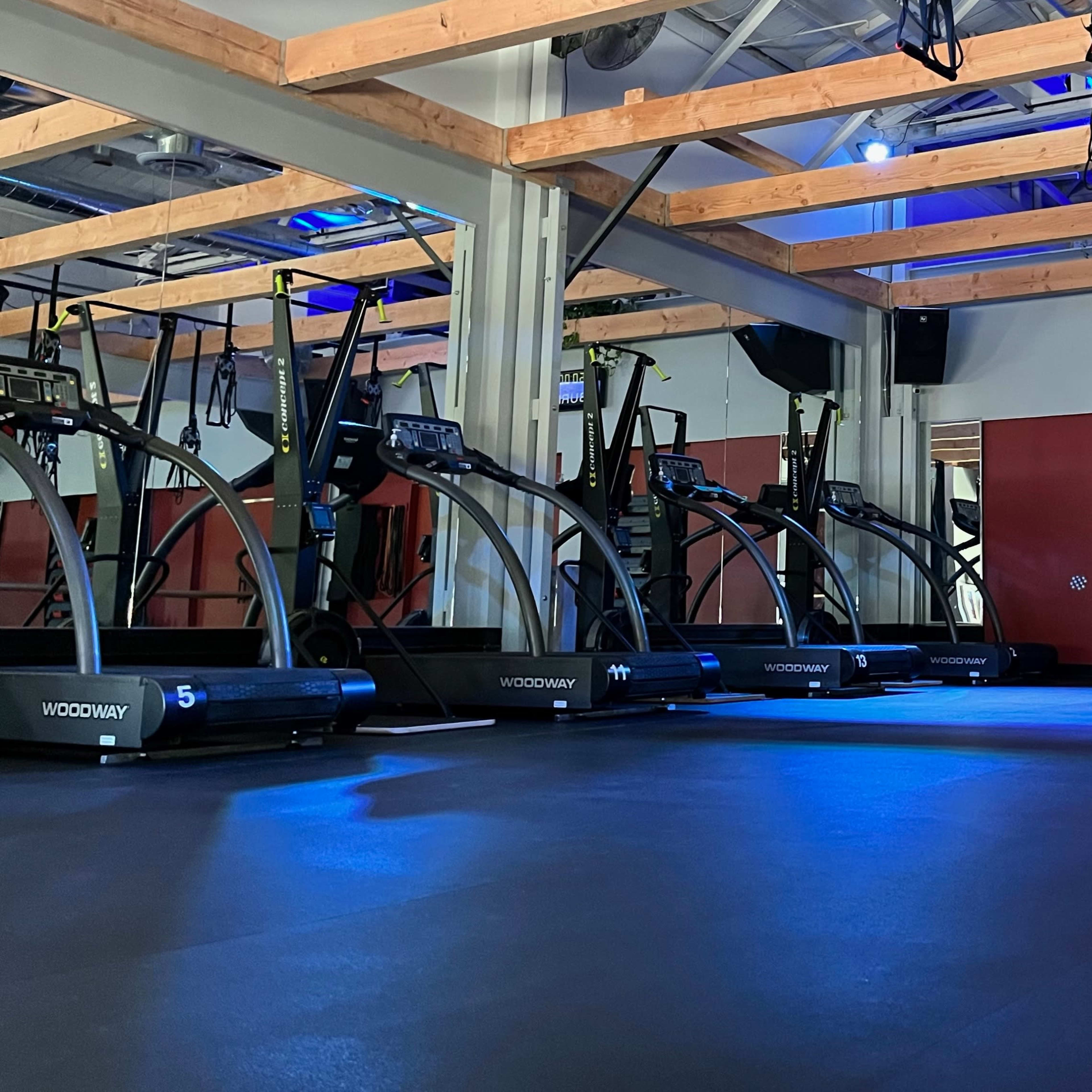 A fitness studio with various cardio machines, exercise bands, and a spacious, well-lit interior.