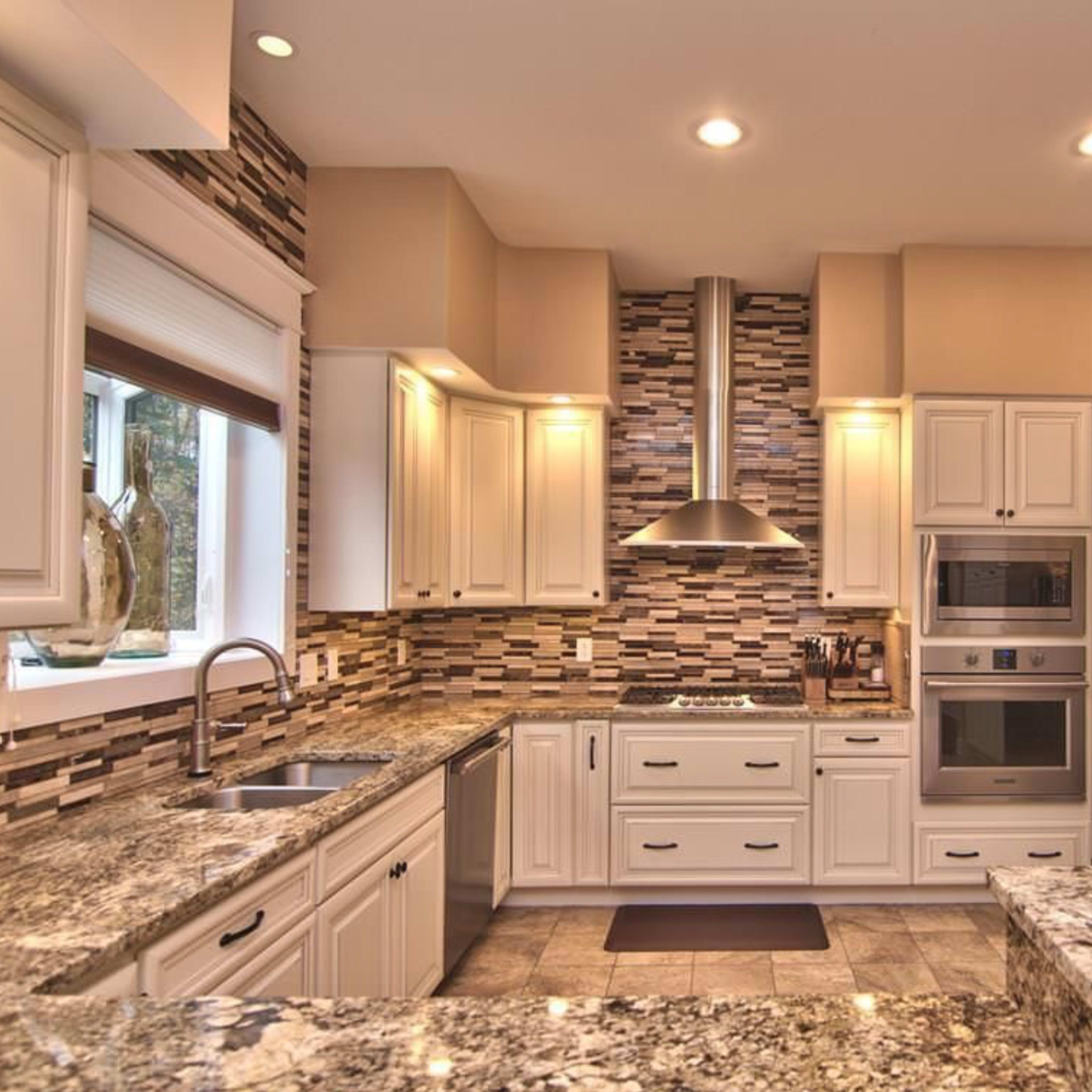 A modern kitchen with white cabinetry, granite countertops, and stainless steel appliances.
