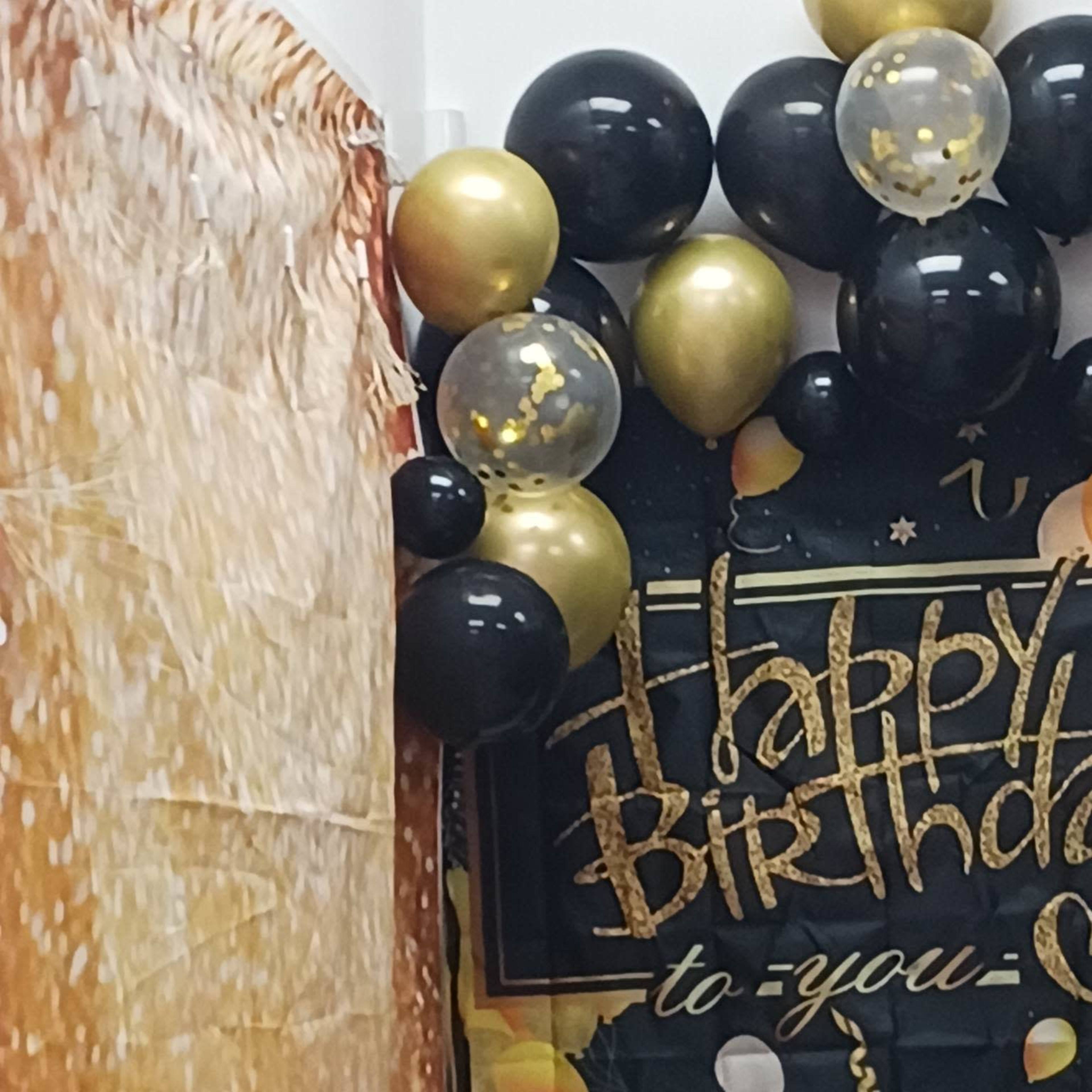 A birthday decoration scene with black, gold, and clear balloons, alongside a banner that reads "Happy Birthday to you."