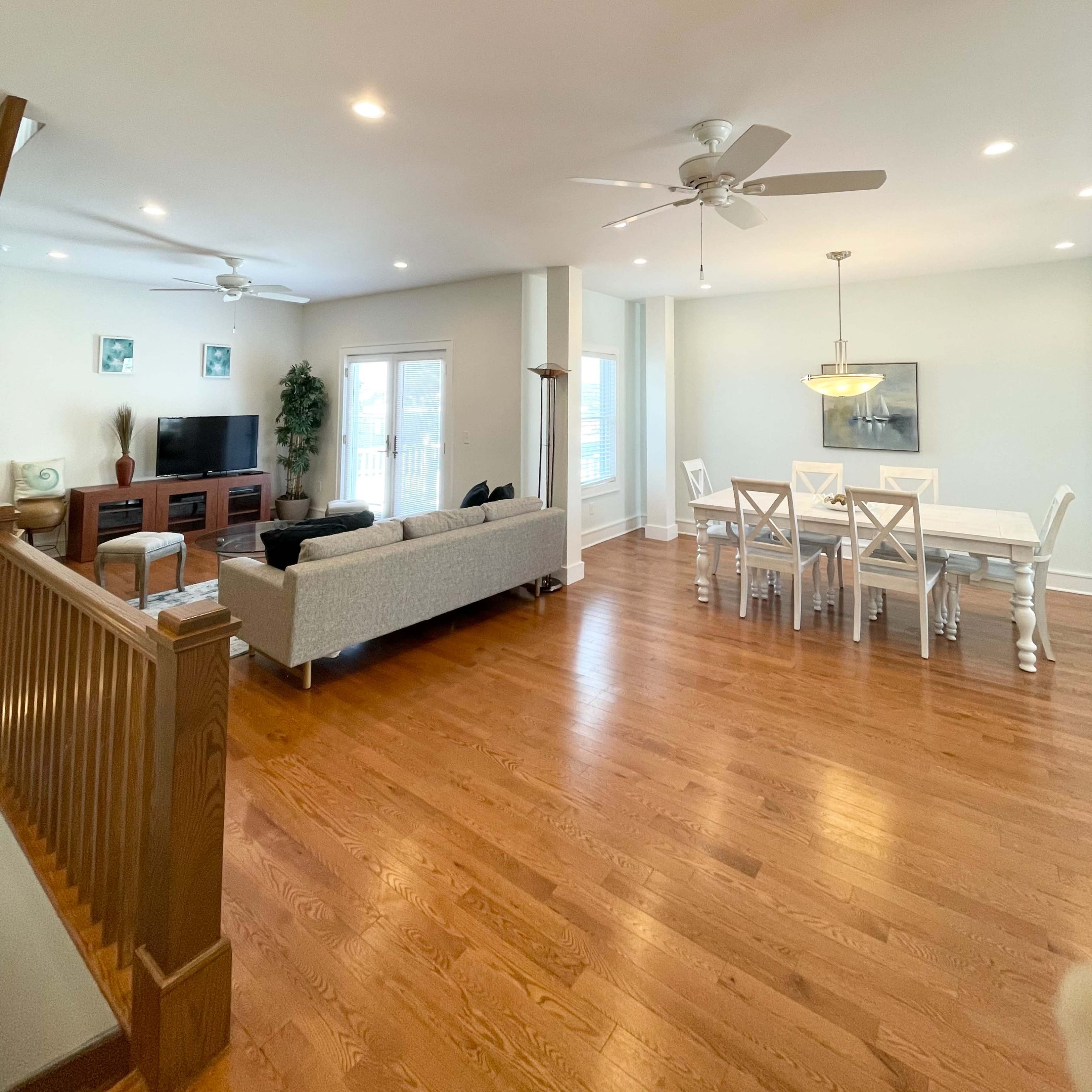 The room features an open layout with a living area containing a sofa and television, and a dining area with a table and chairs.
