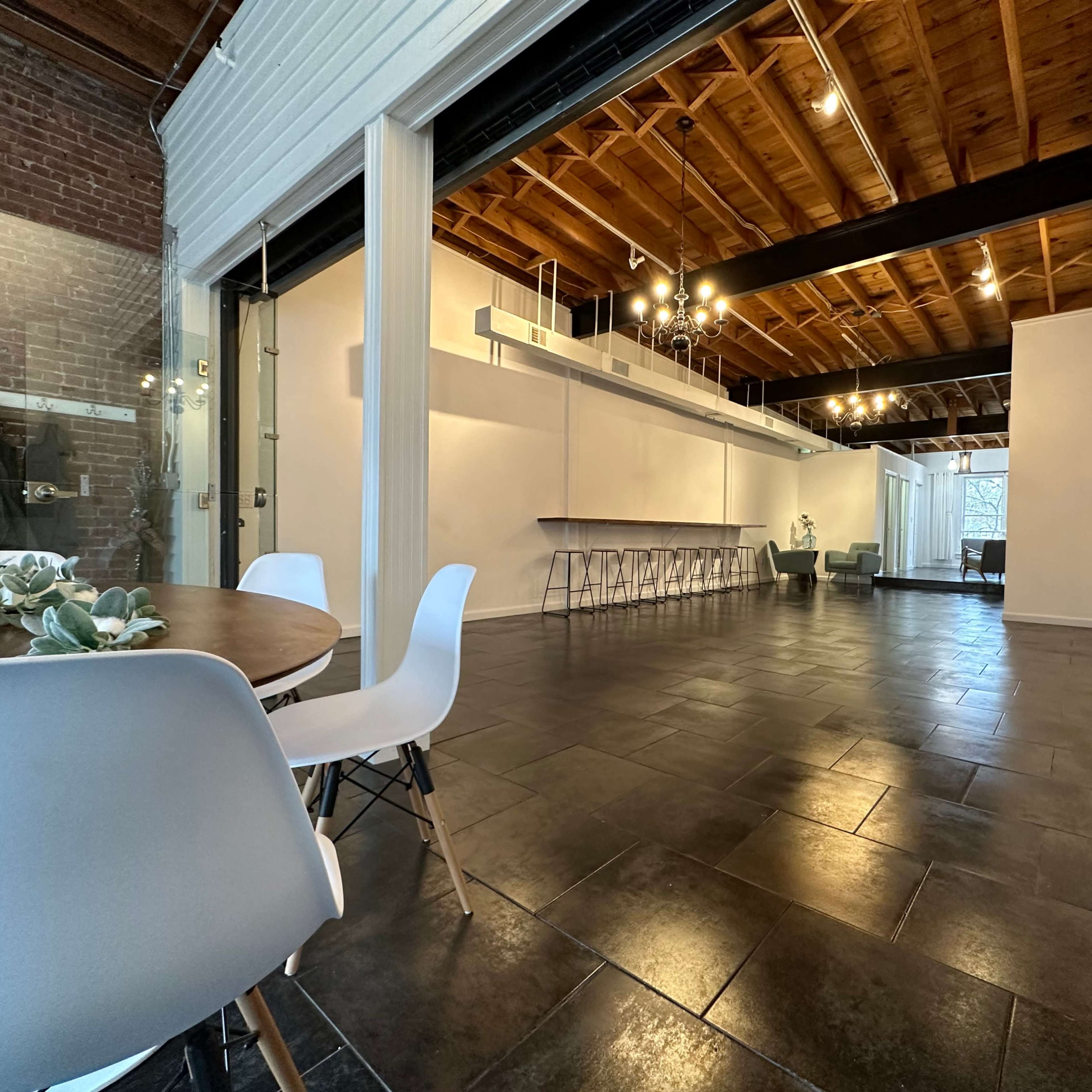A spacious interior with a dining area featuring a round table and chairs, and an open area with a bar-like counter and multiple seating options.