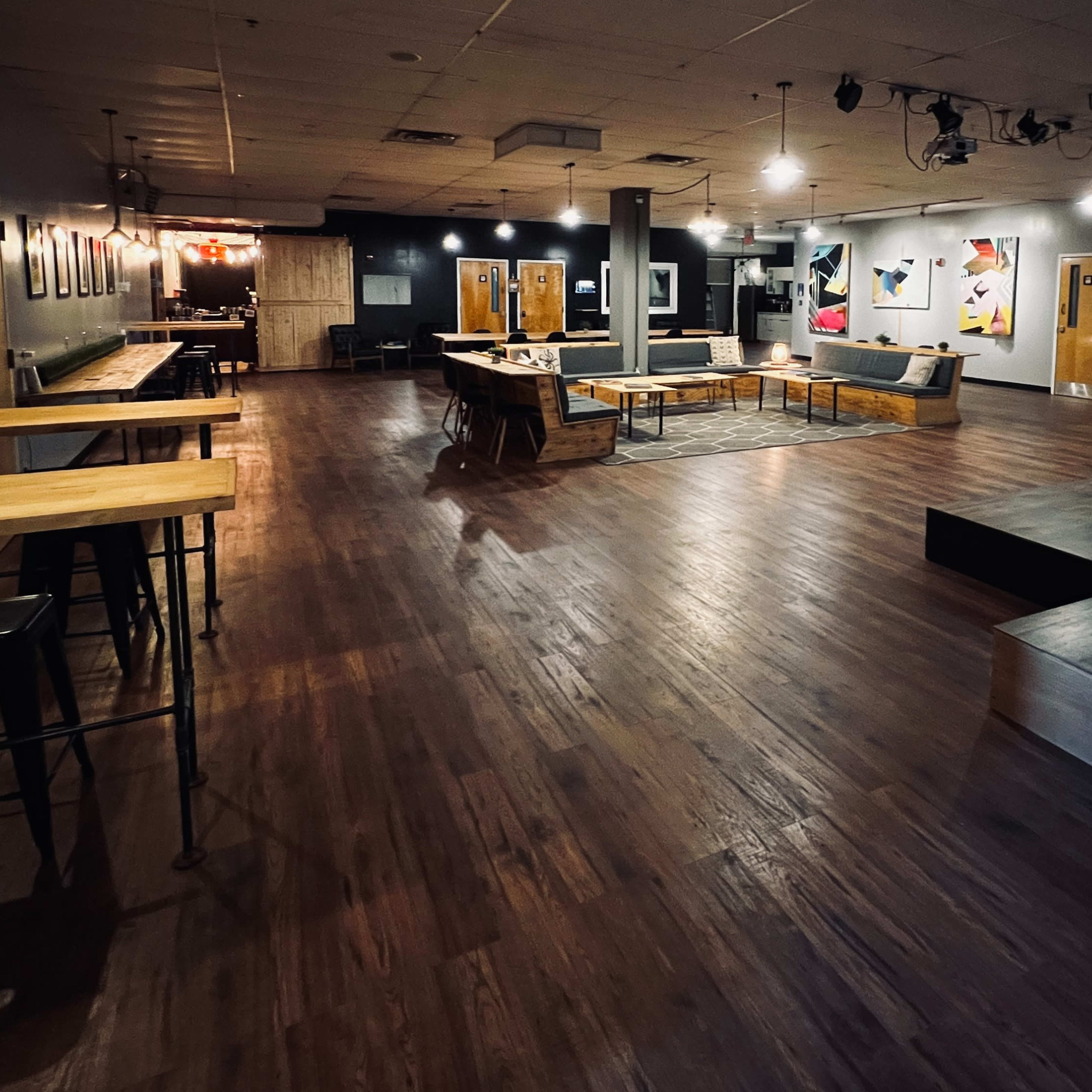 A spacious and well-lit interior featuring wooden flooring, seating areas, and walls adorned with artwork.