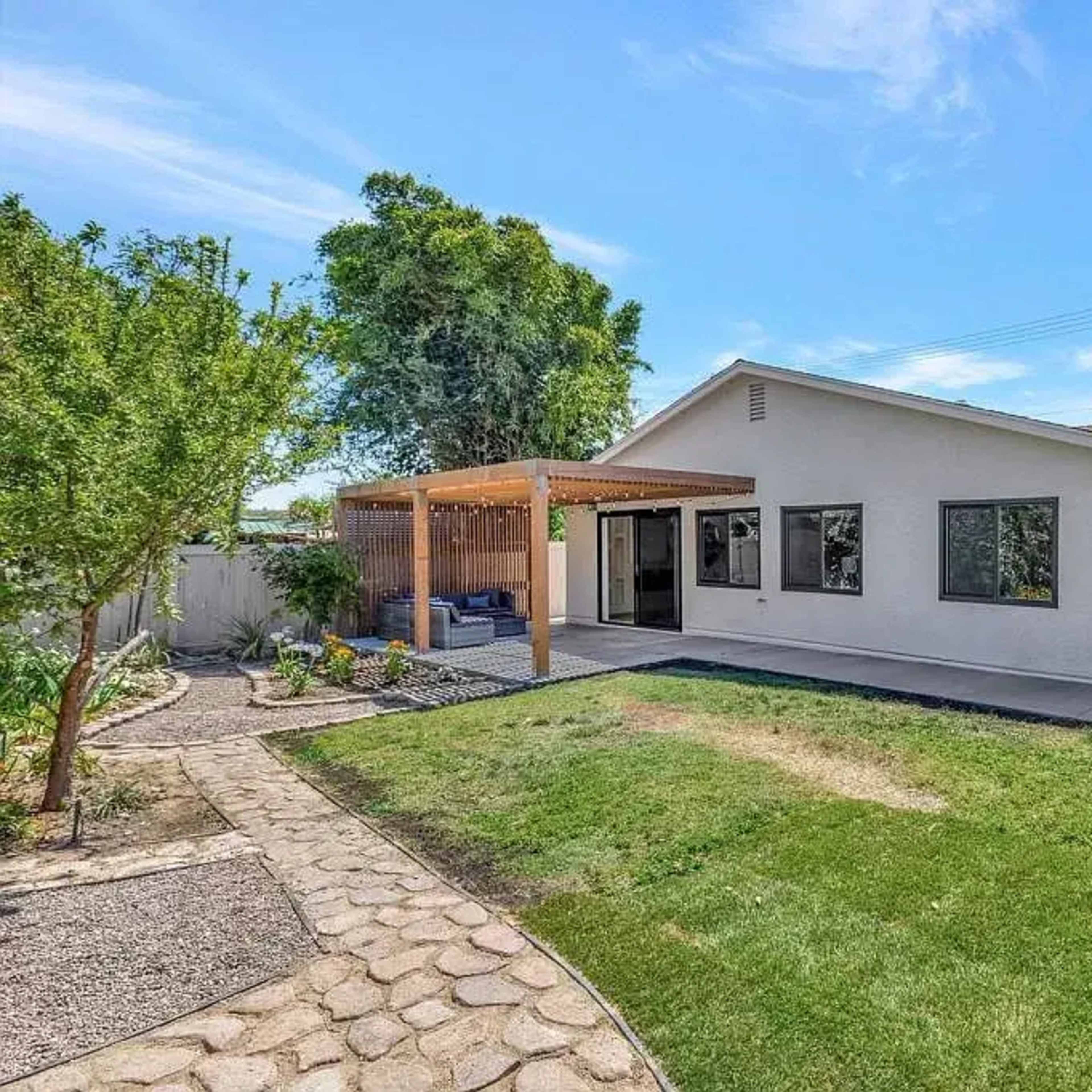 A spacious backyard with a patio, well-maintained lawn, and a pathway leading to a nearby garden area.