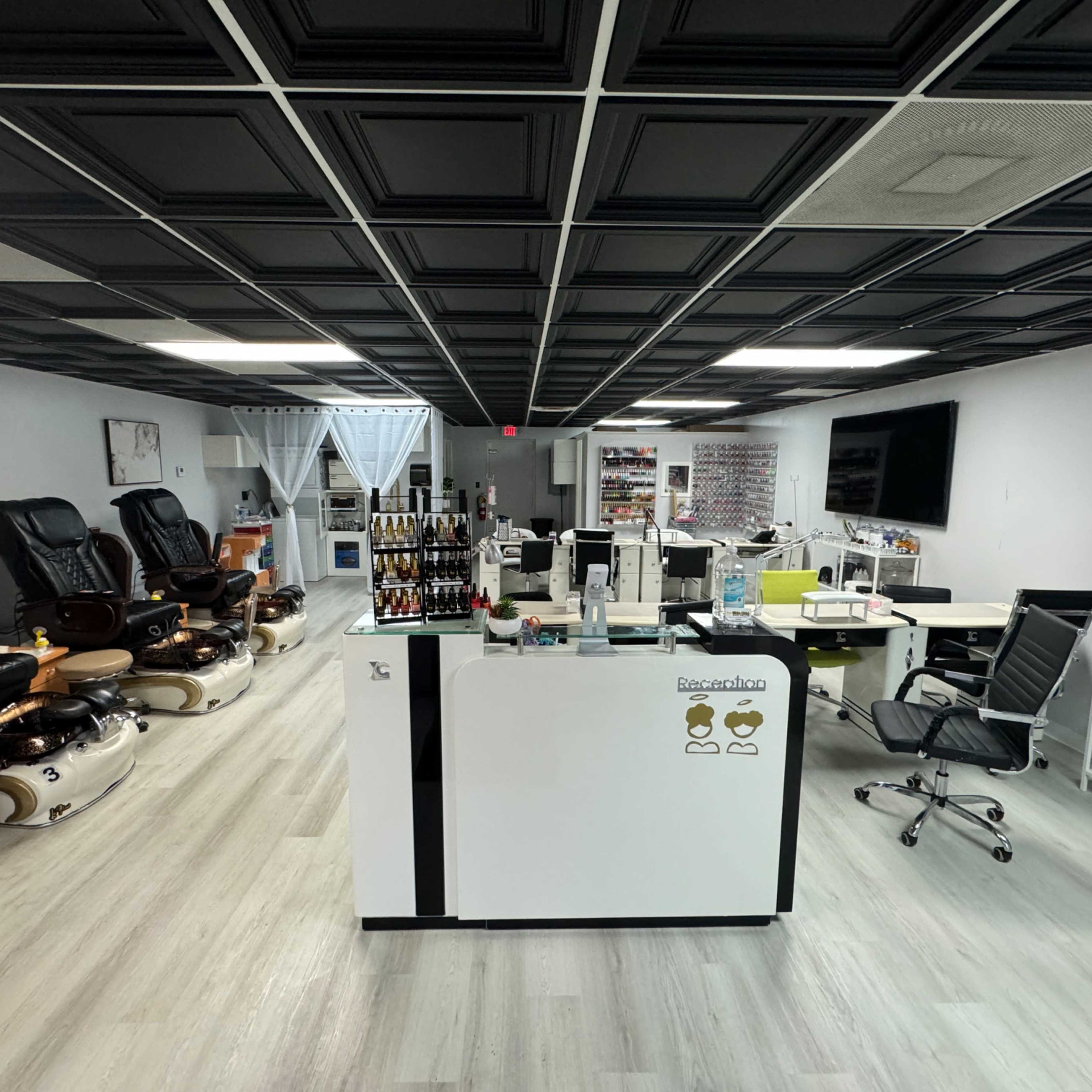 A modern nail salon with a reception desk, several pedicure chairs, and a well-organized display of nail products.