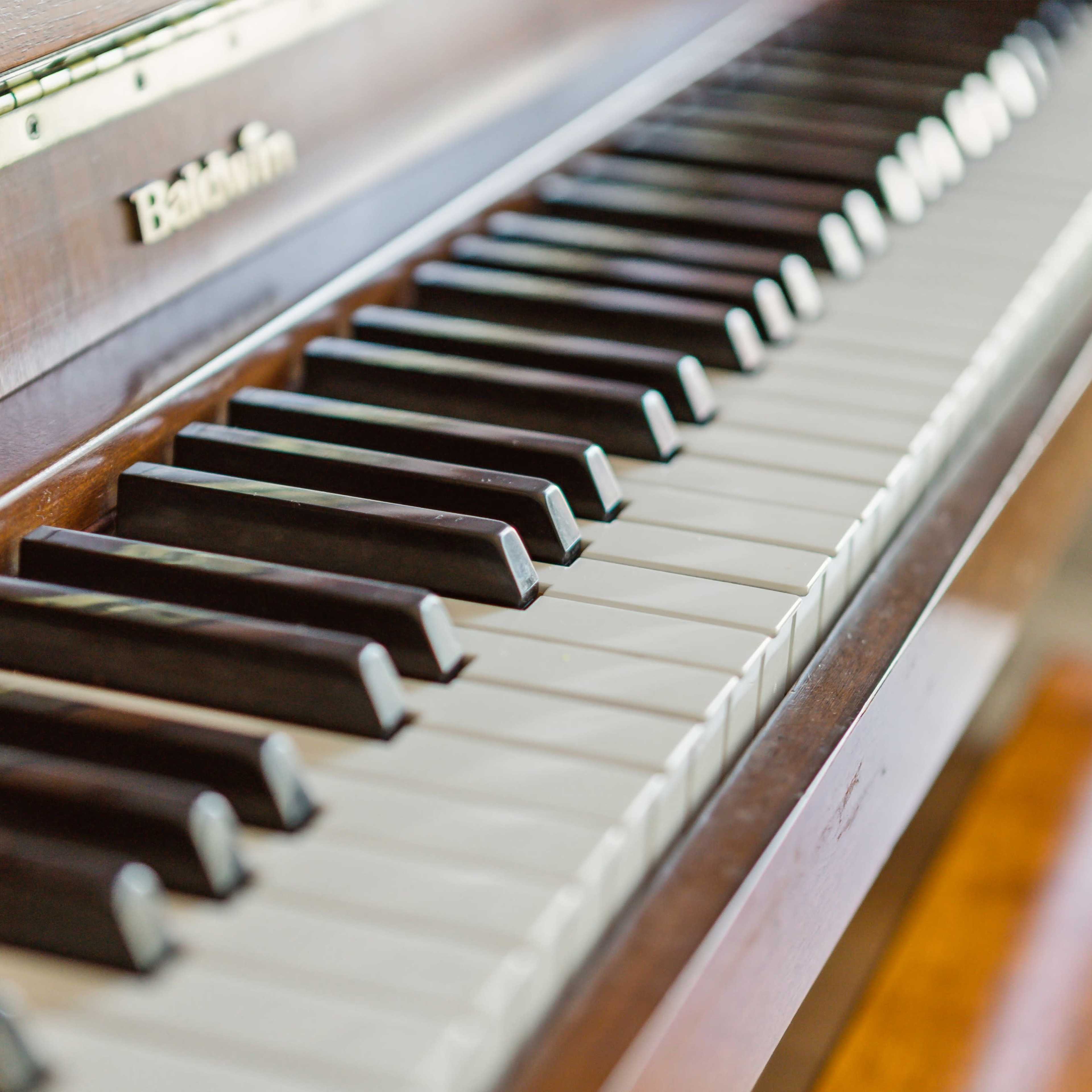 The keys of a wooden piano with a focus on the black and white keys.
