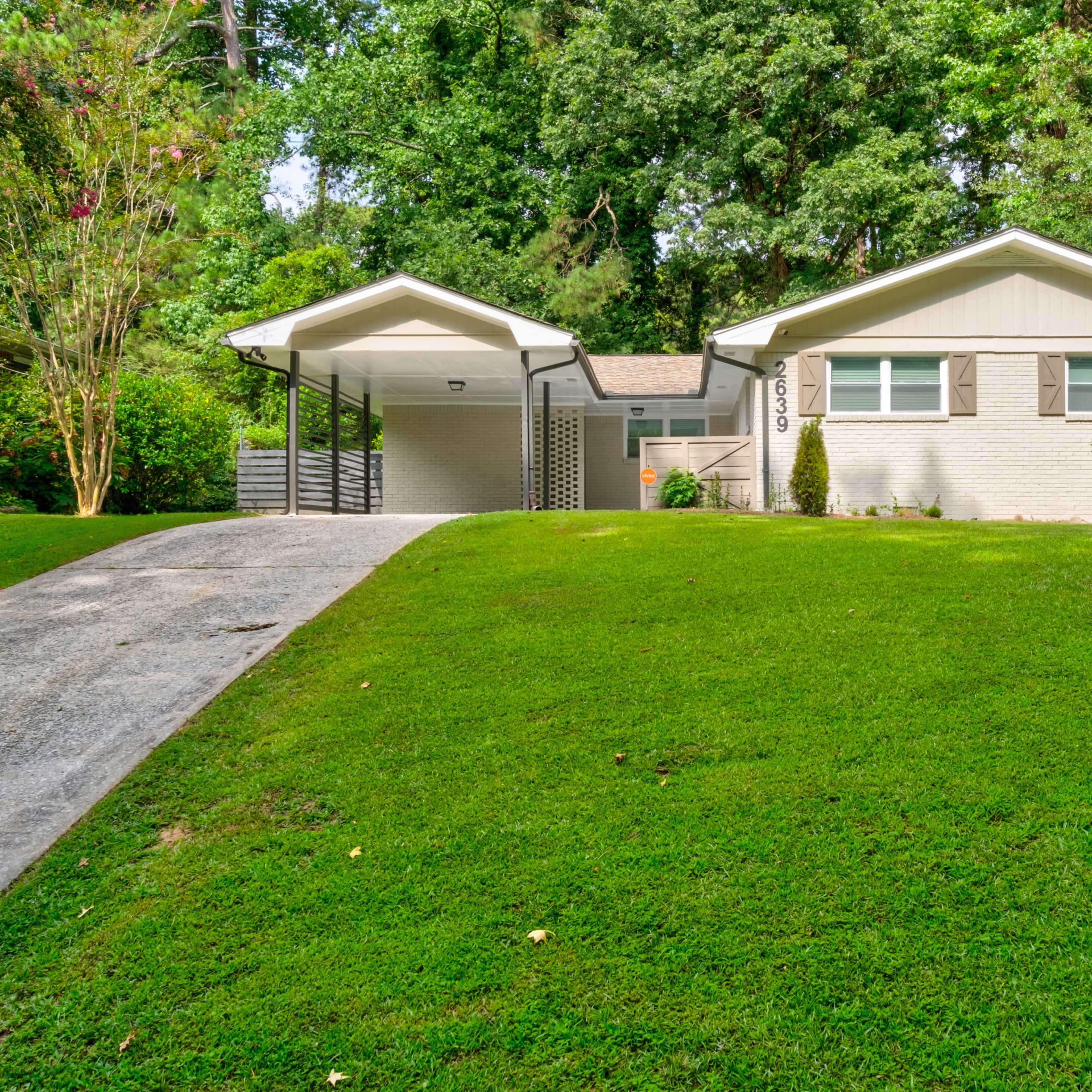 A single-story residential home with a landscaped front yard and a gravel driveway leading up to it.