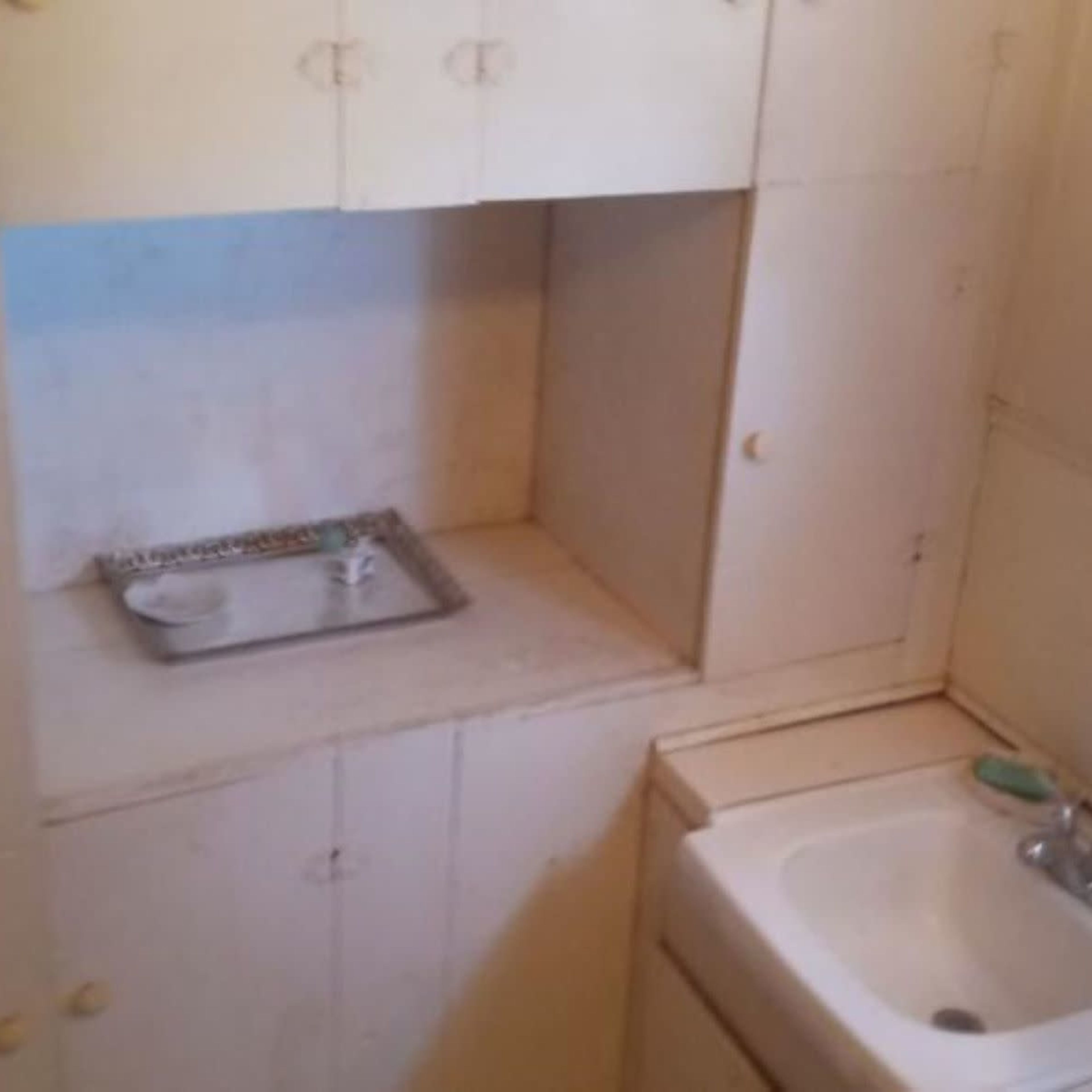 A small bathroom with a sink and a cabinet area, partially obscured by a shower curtain.