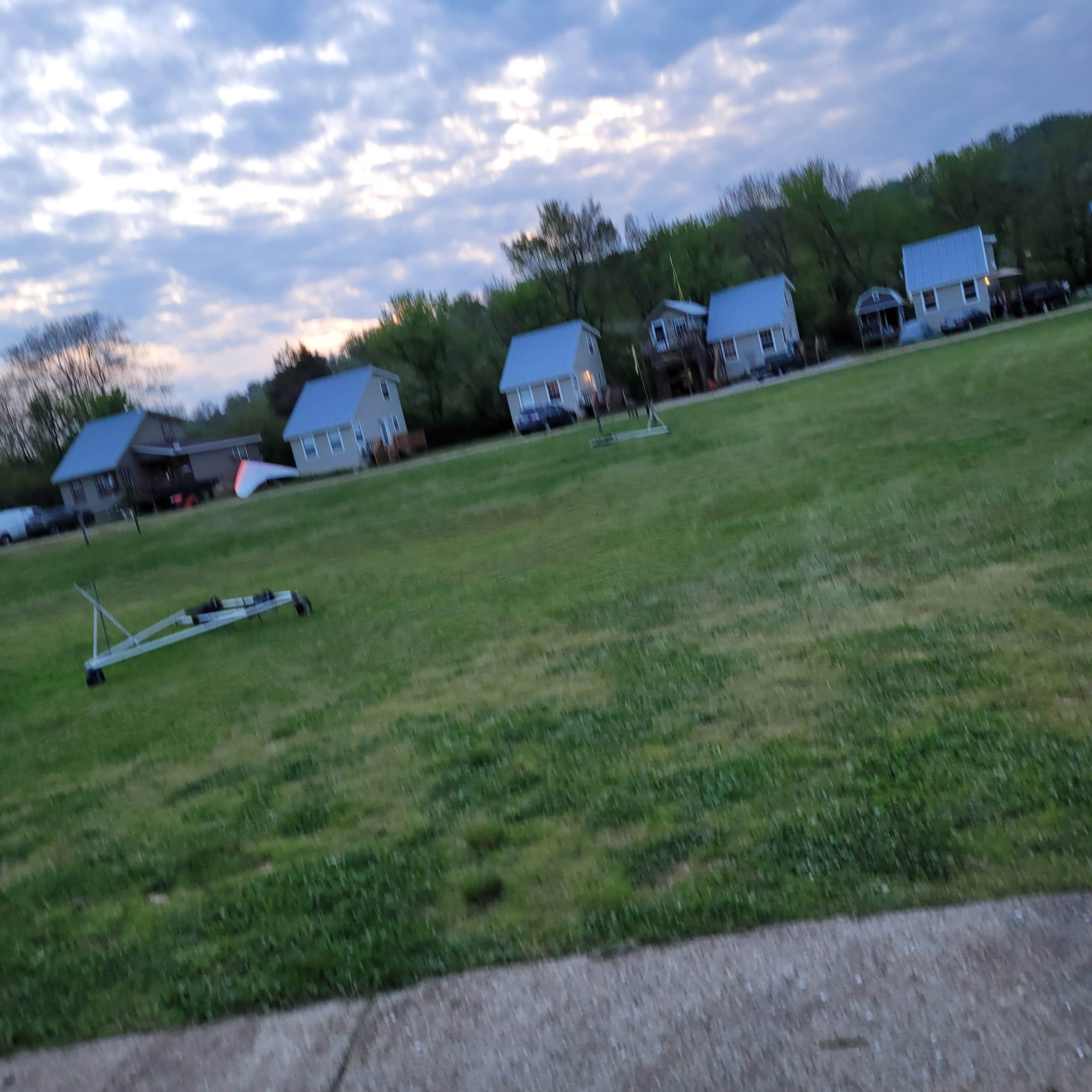 A grassy area in front of several houses under a cloudy sky.